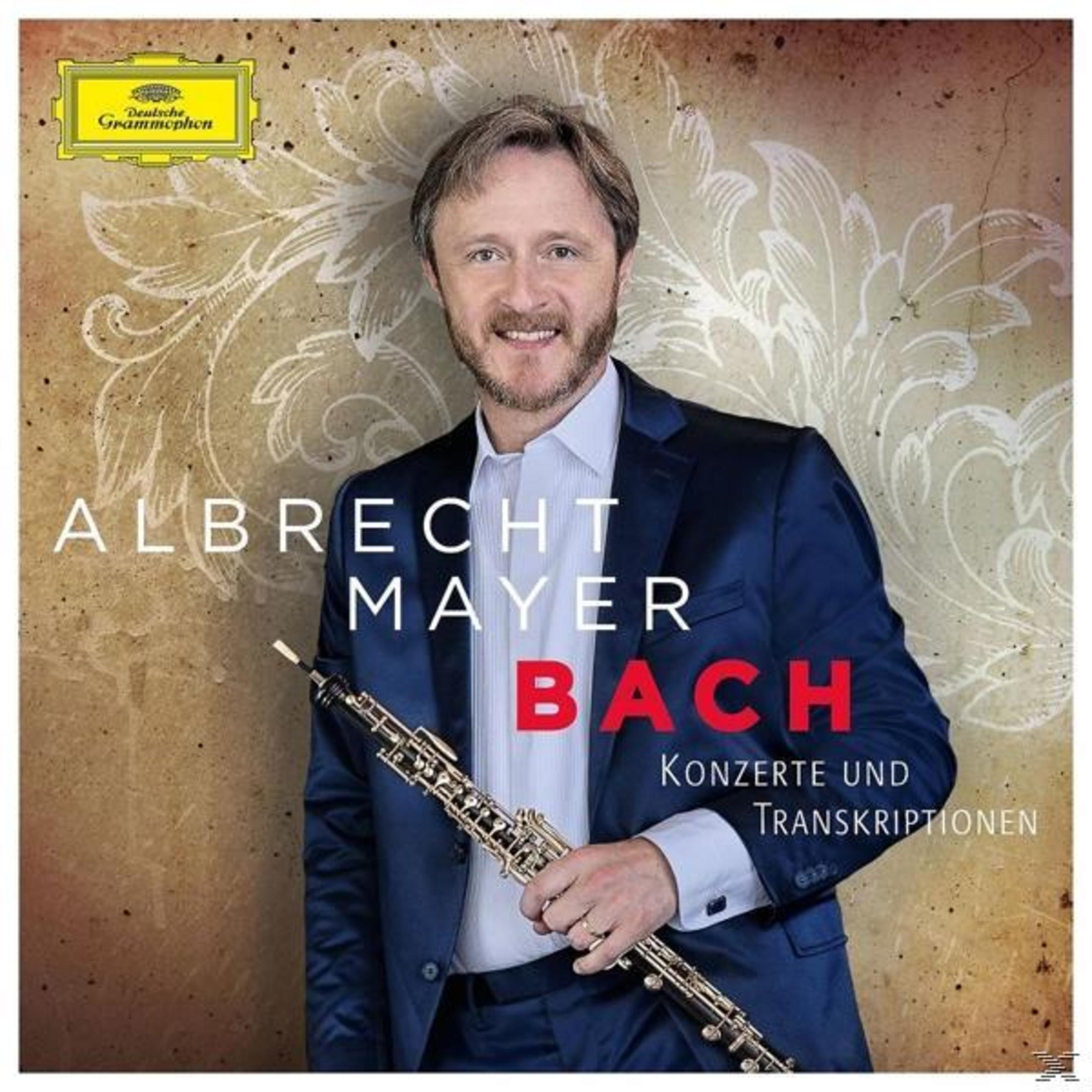 Albrecht Mayer im blauen Anzug hält eine Oboe vor ornamentalem Hintergrund mit Text.