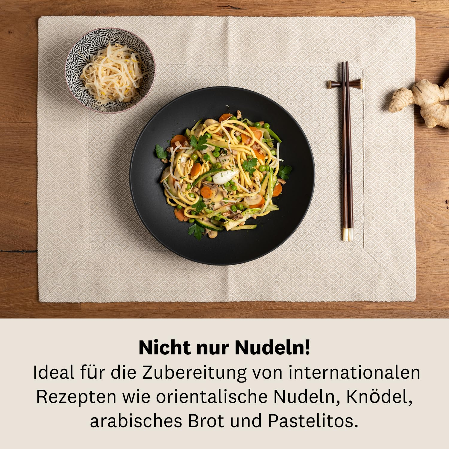 Bol noir avec nouilles et légumes sur set de table clair avec baguettes et gingembre.
