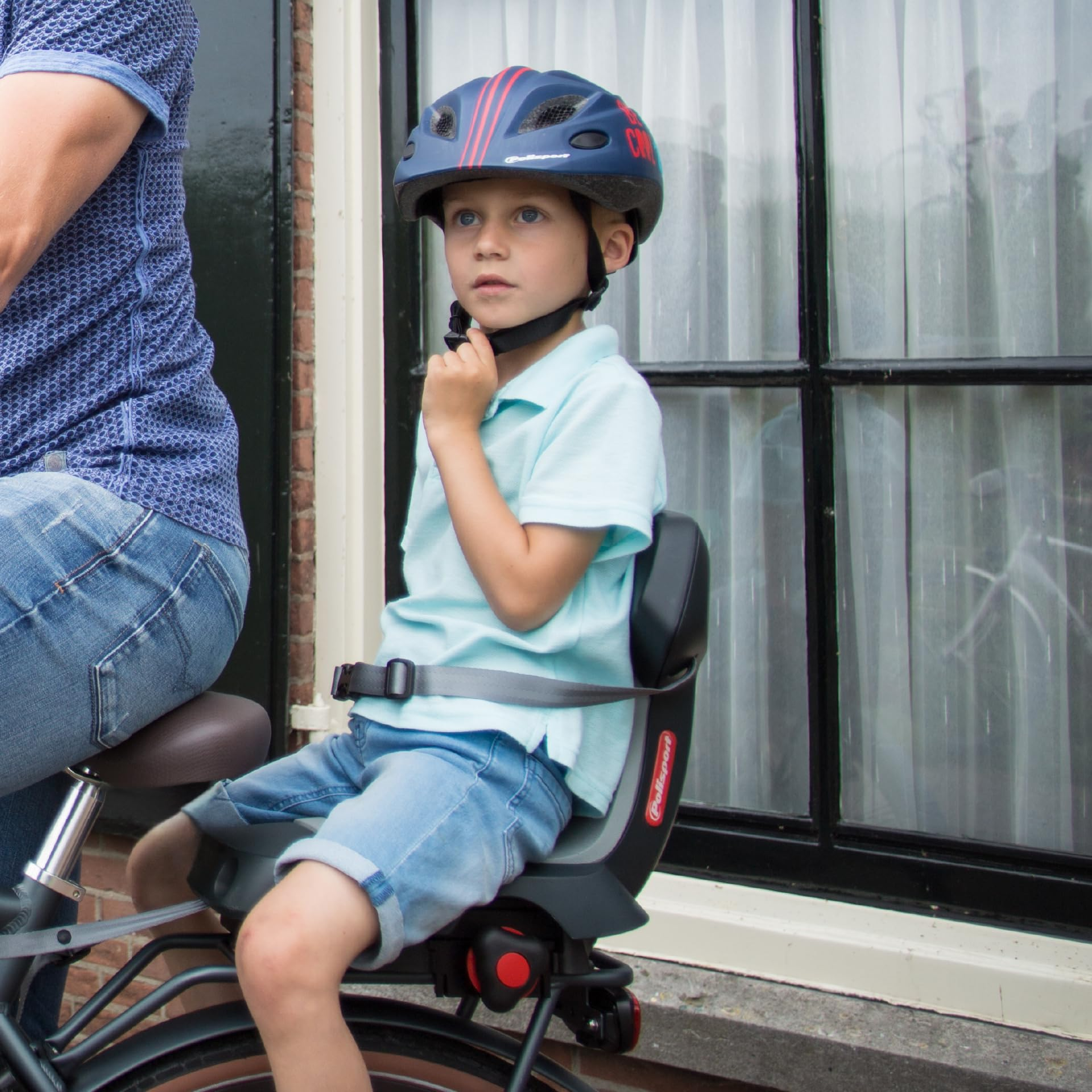 Un ragazzo con casco blu e polo siede legato su un seggiolino per bici.