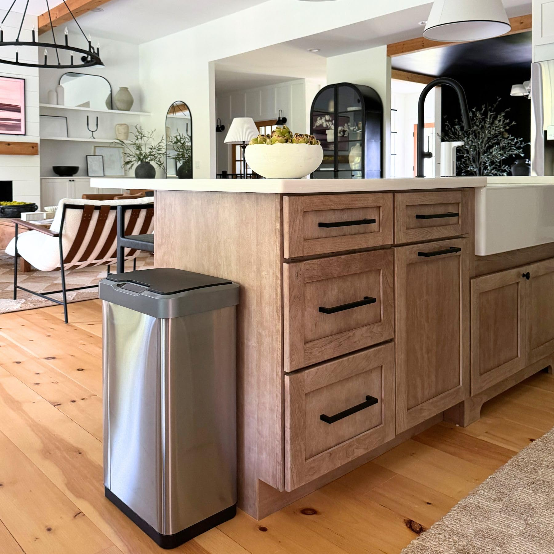 Moderne Küche mit Holzinsel und Edelstahl-Mülleimer im Vordergrund.