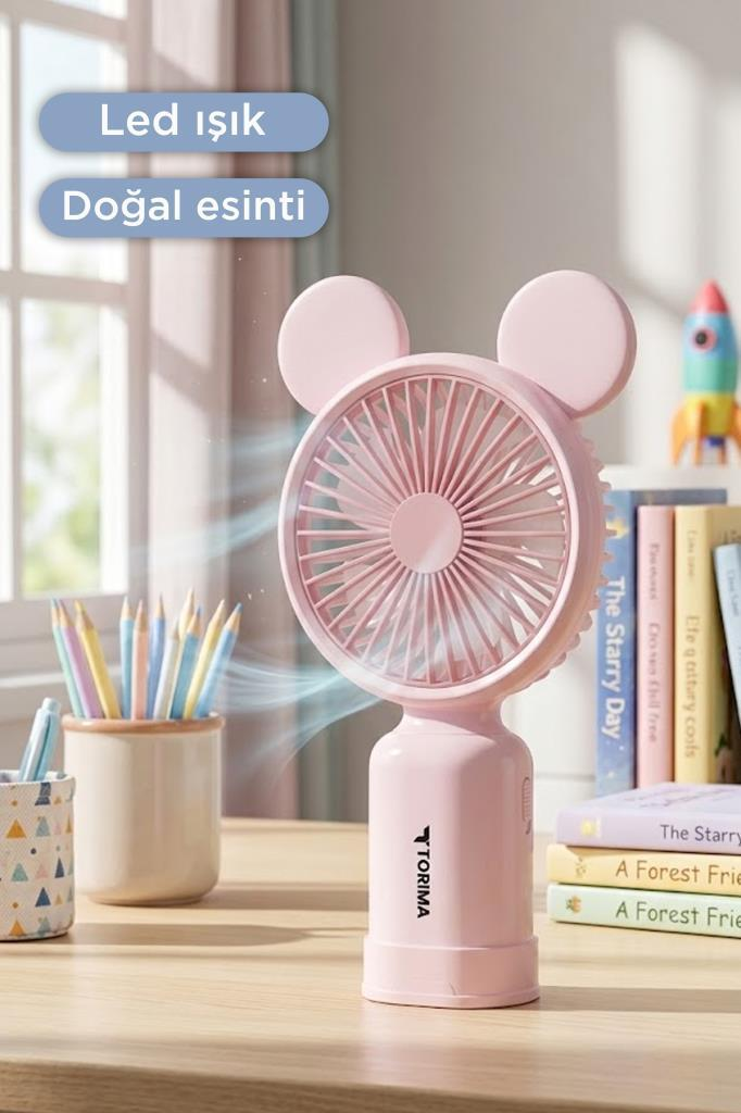 Pembe fare kulaklı masa fanı tahta masaya hava üflüyor, arkada kalemler ve kitaplar var.