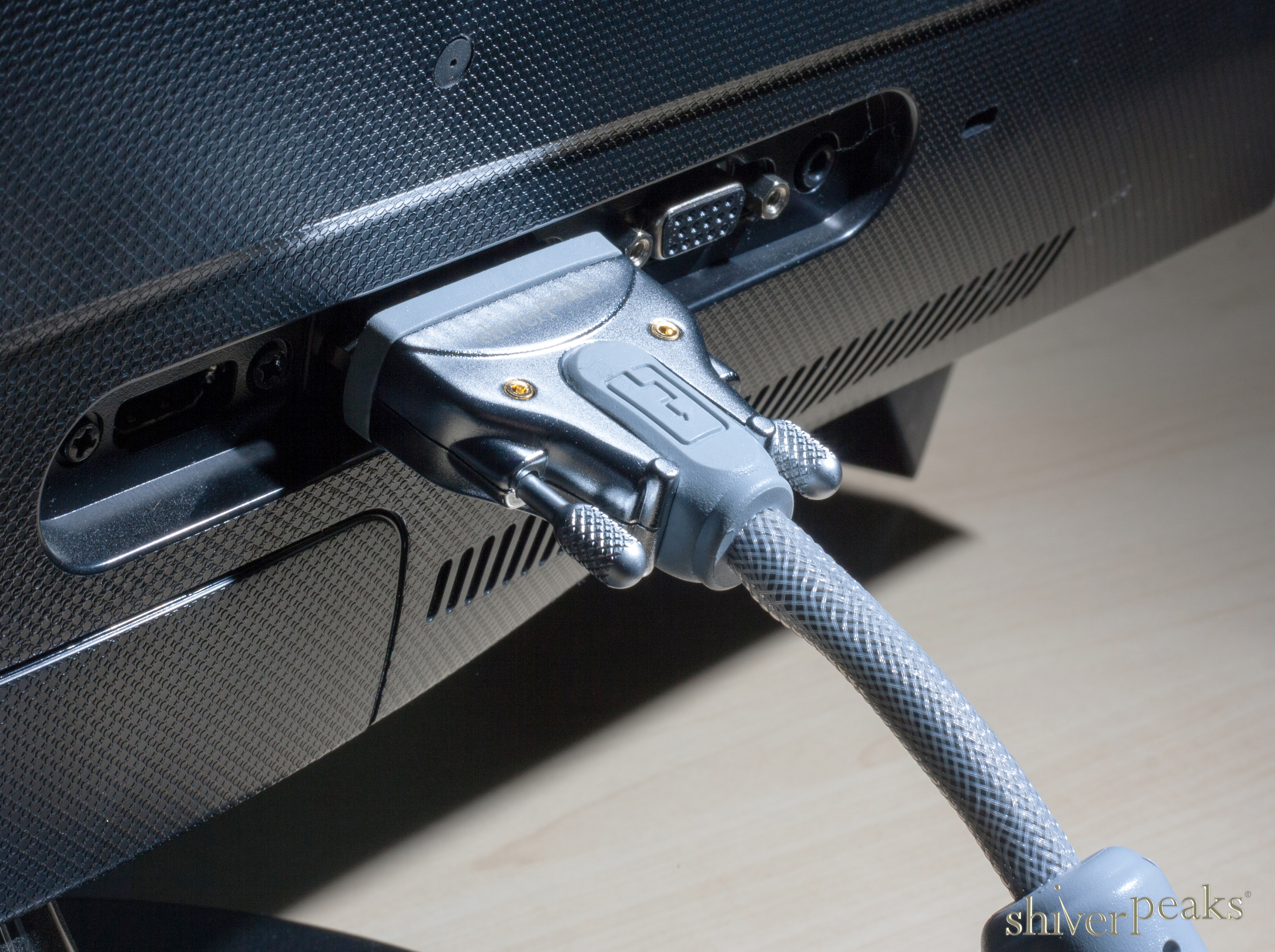Ein graues VGA-Kabel ist an die Rückseite eines schwarzen Monitors angeschlossen.