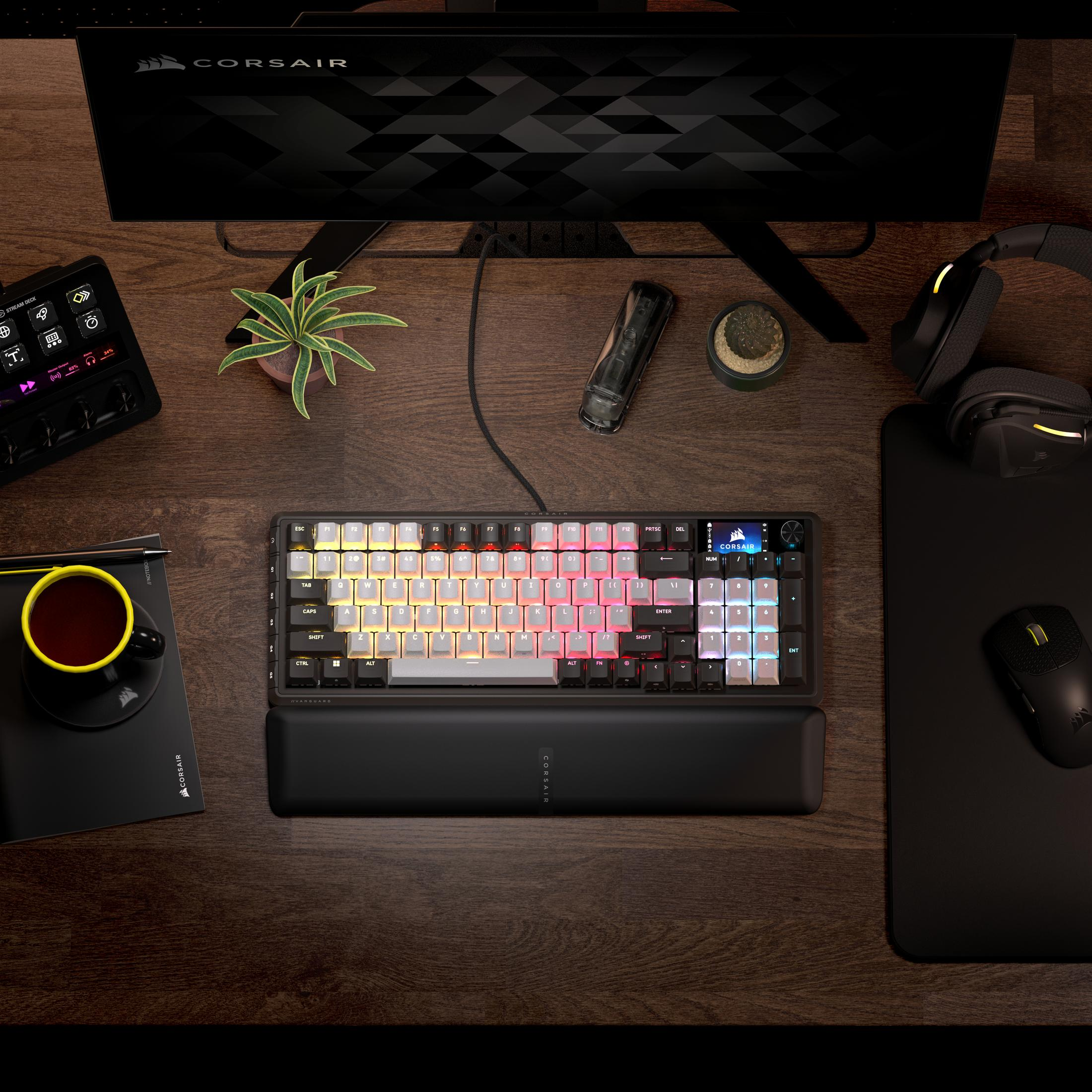Una scrivania in legno con tastiera RGB, mouse, monitor, cuffie e una tazza di caffè.