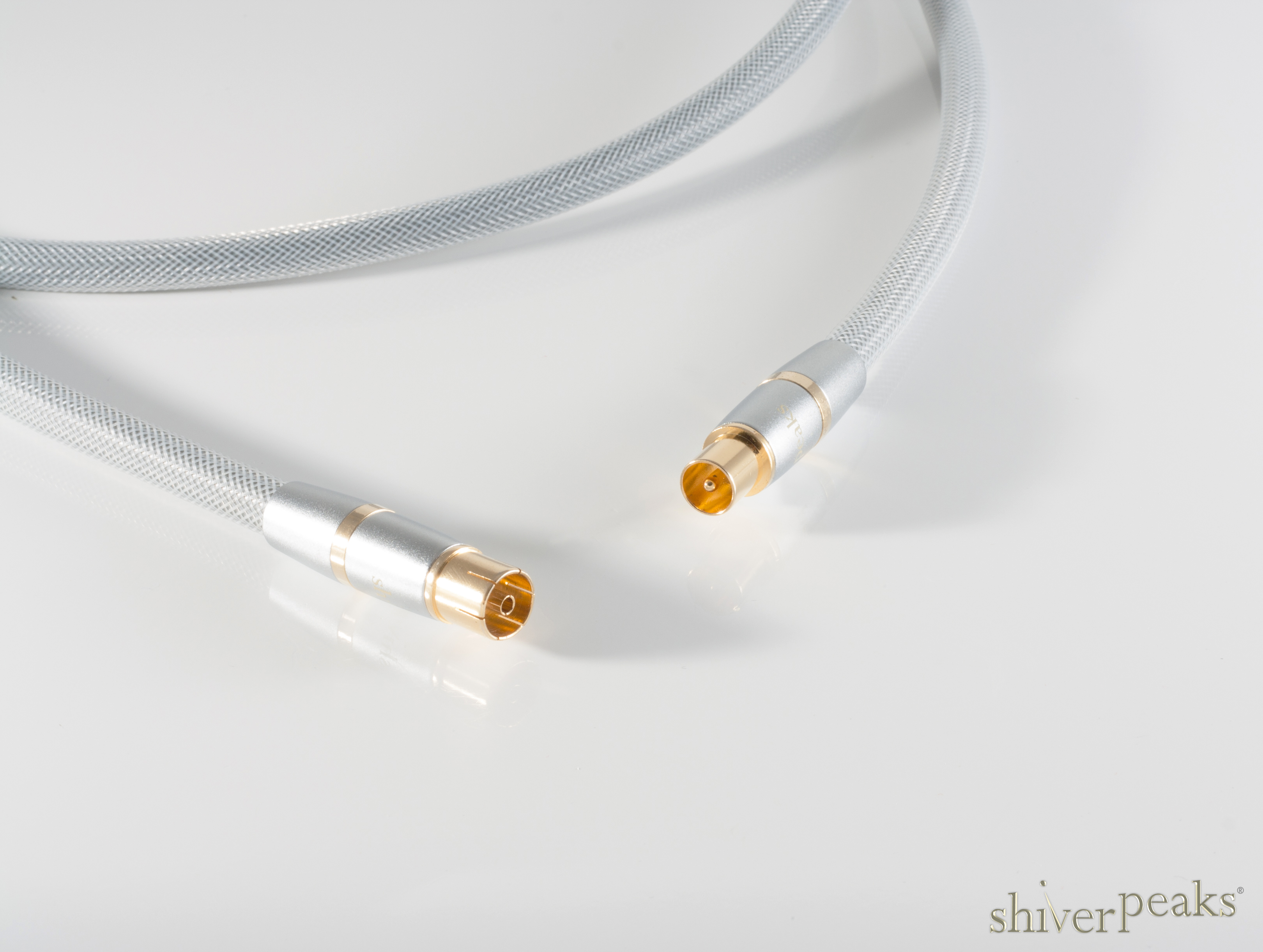 Ein graues Koaxialkabel mit goldenen Anschlüssen liegt auf einer hellen Oberfläche.