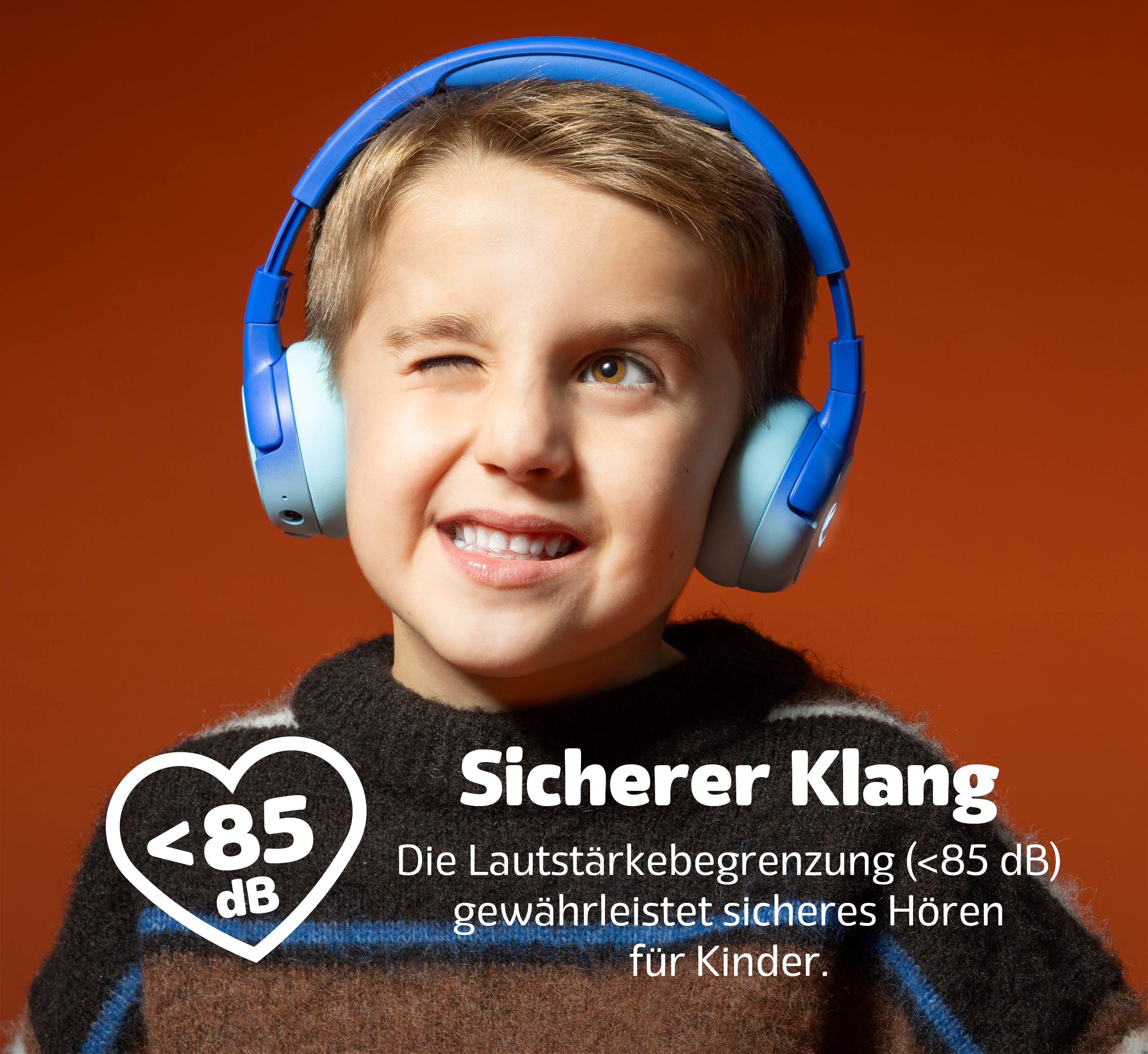 Ein Junge mit blauen Kopfhörern winkt und zeigt Text zum sicheren Hören.