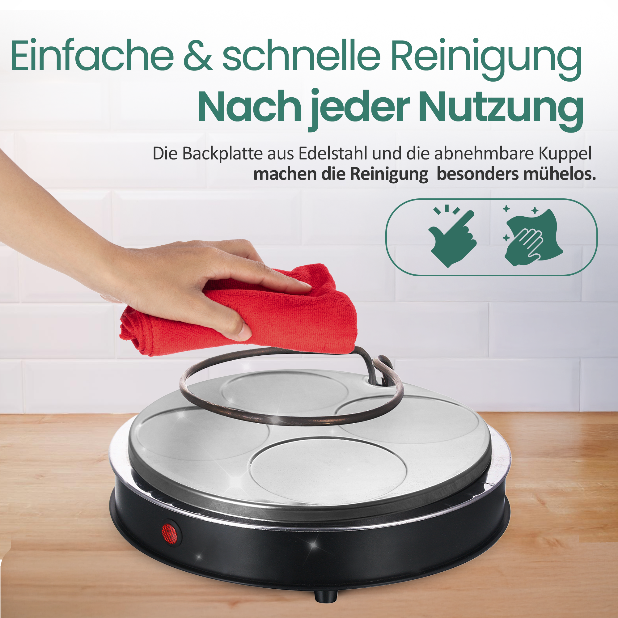 Hand wischt eine runde, schwarze Kochplatte auf einer Holzarbeitsplatte mit weißem Fliesenwand-Hintergrund sauber.