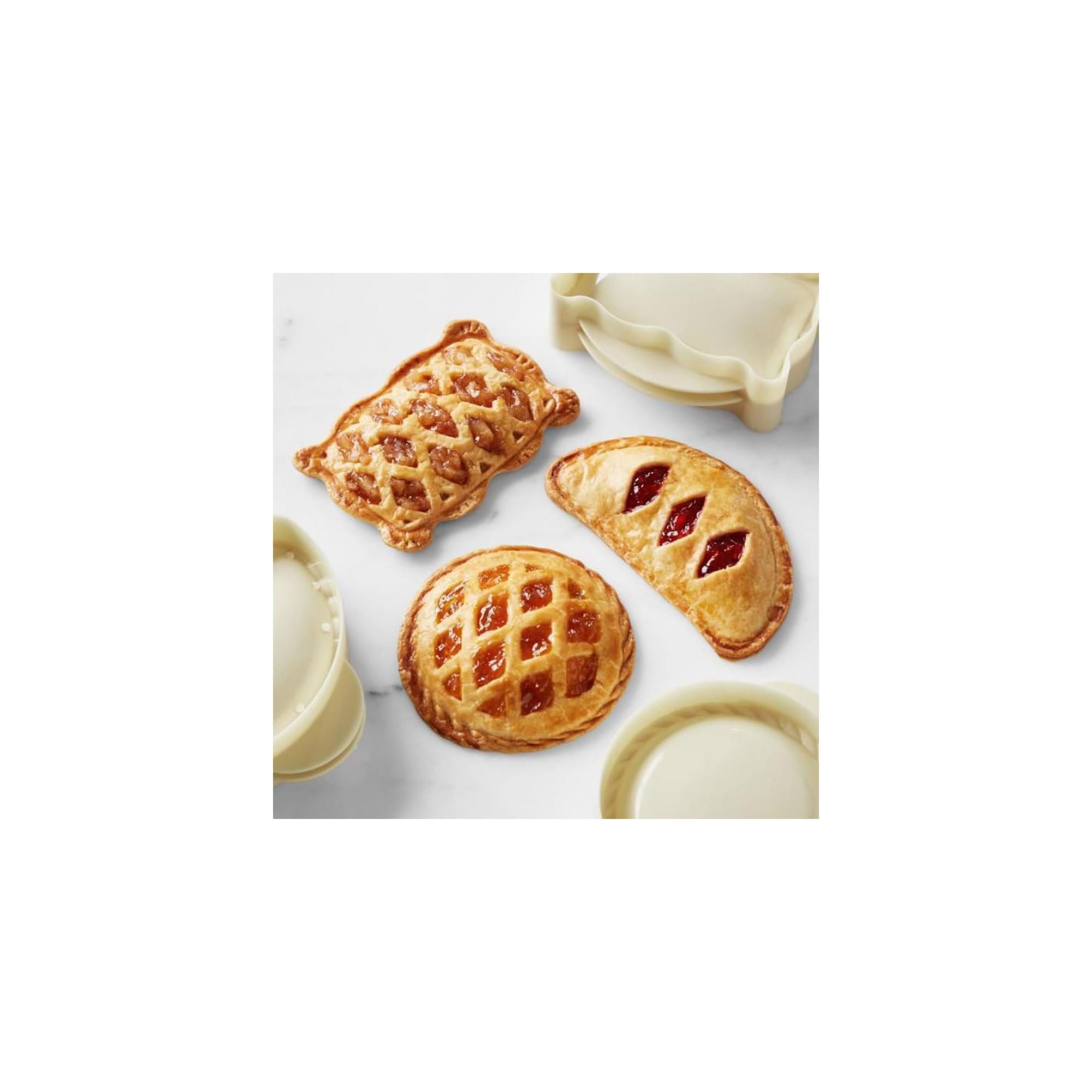 Drei verschiedene gebackene Mini-Kuchen mit Füllung und helle Teigförmchen auf weißem Hintergrund.