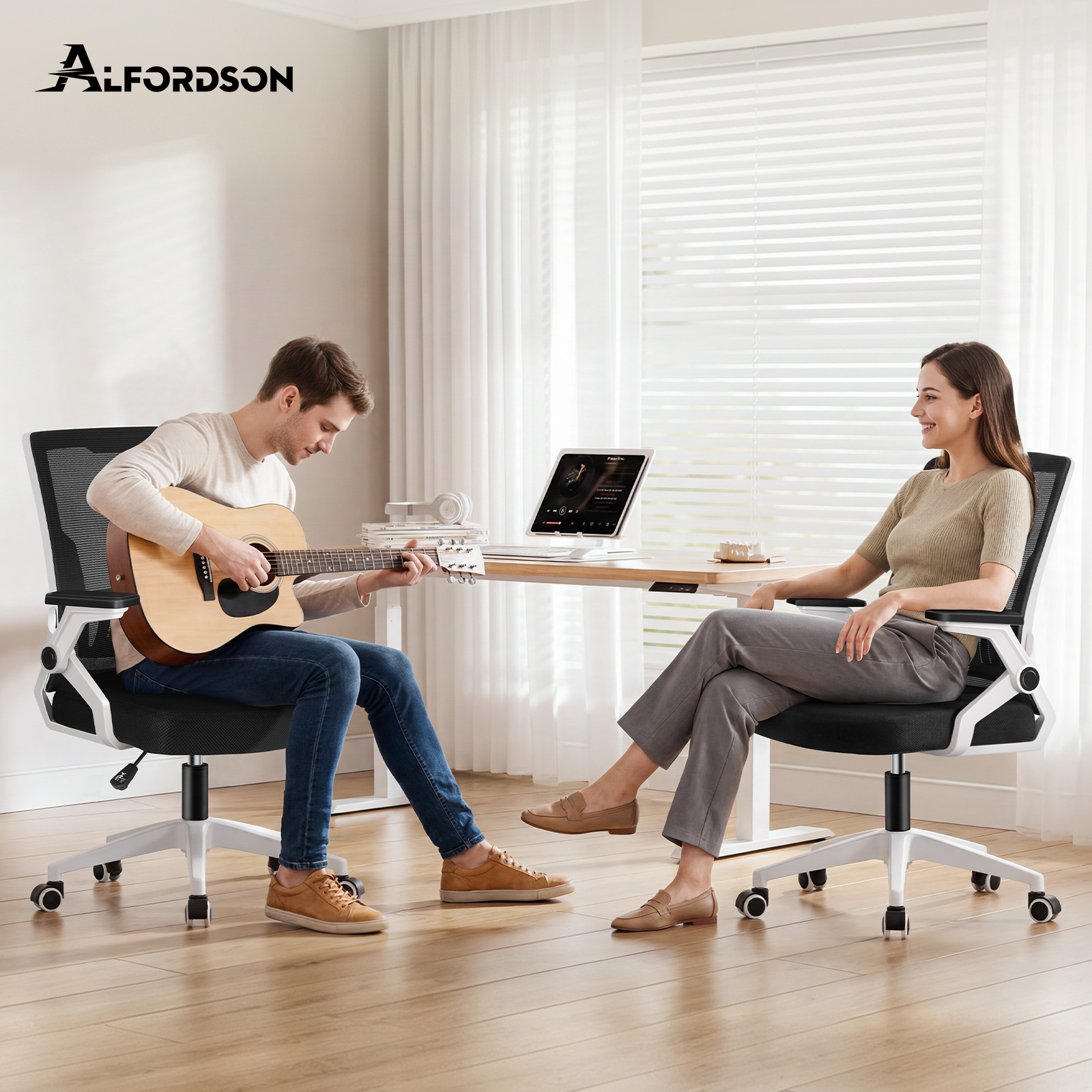 Ein Mann sitzt auf einem Bürostuhl und spielt Gitarre, während eine Frau ihm gegenübersitzt.