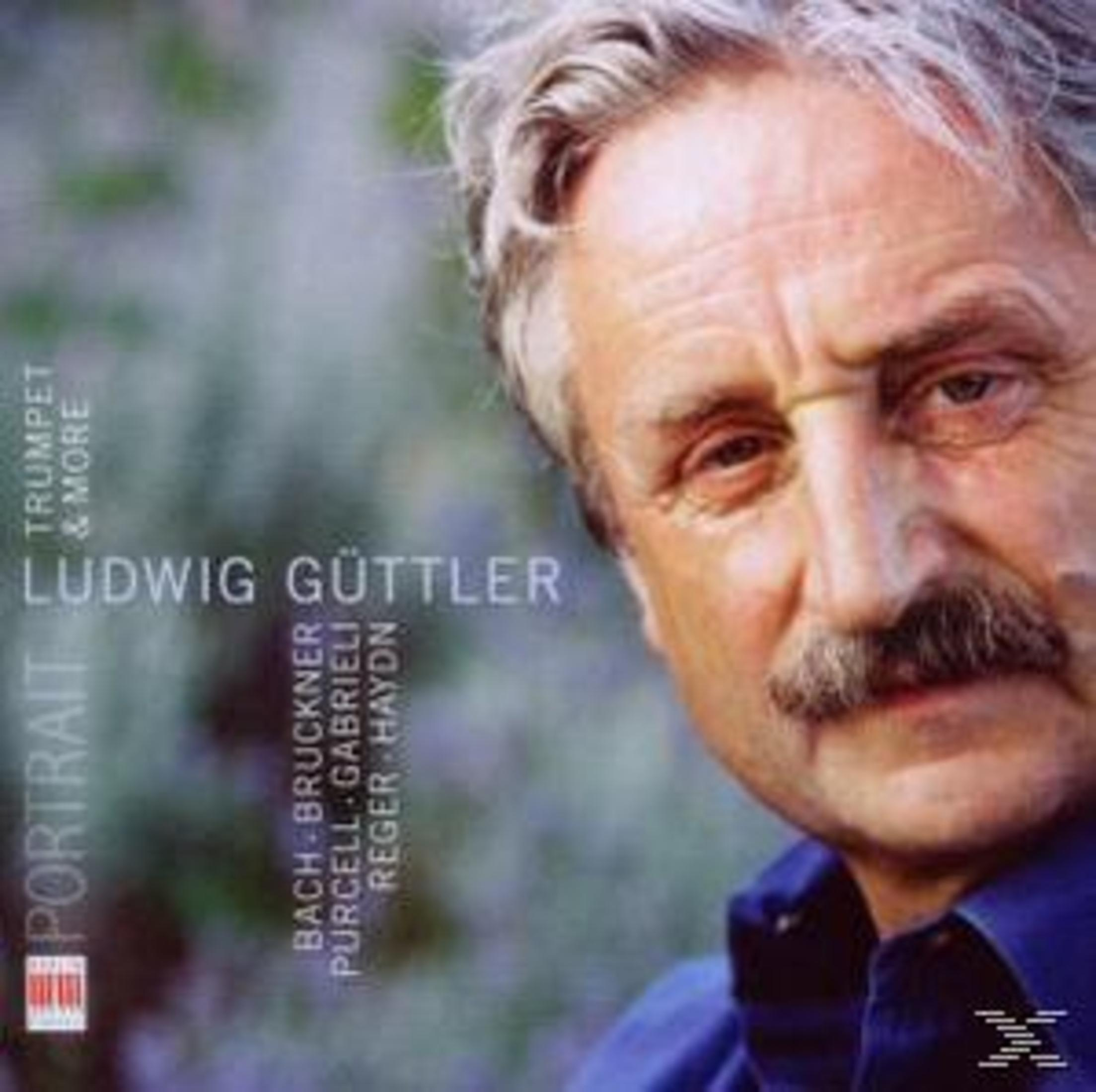 Nahaufnahme von Ludwig Güttler mit Schnurrbart und blauem Hemd vor verschwommenem Hintergrund.