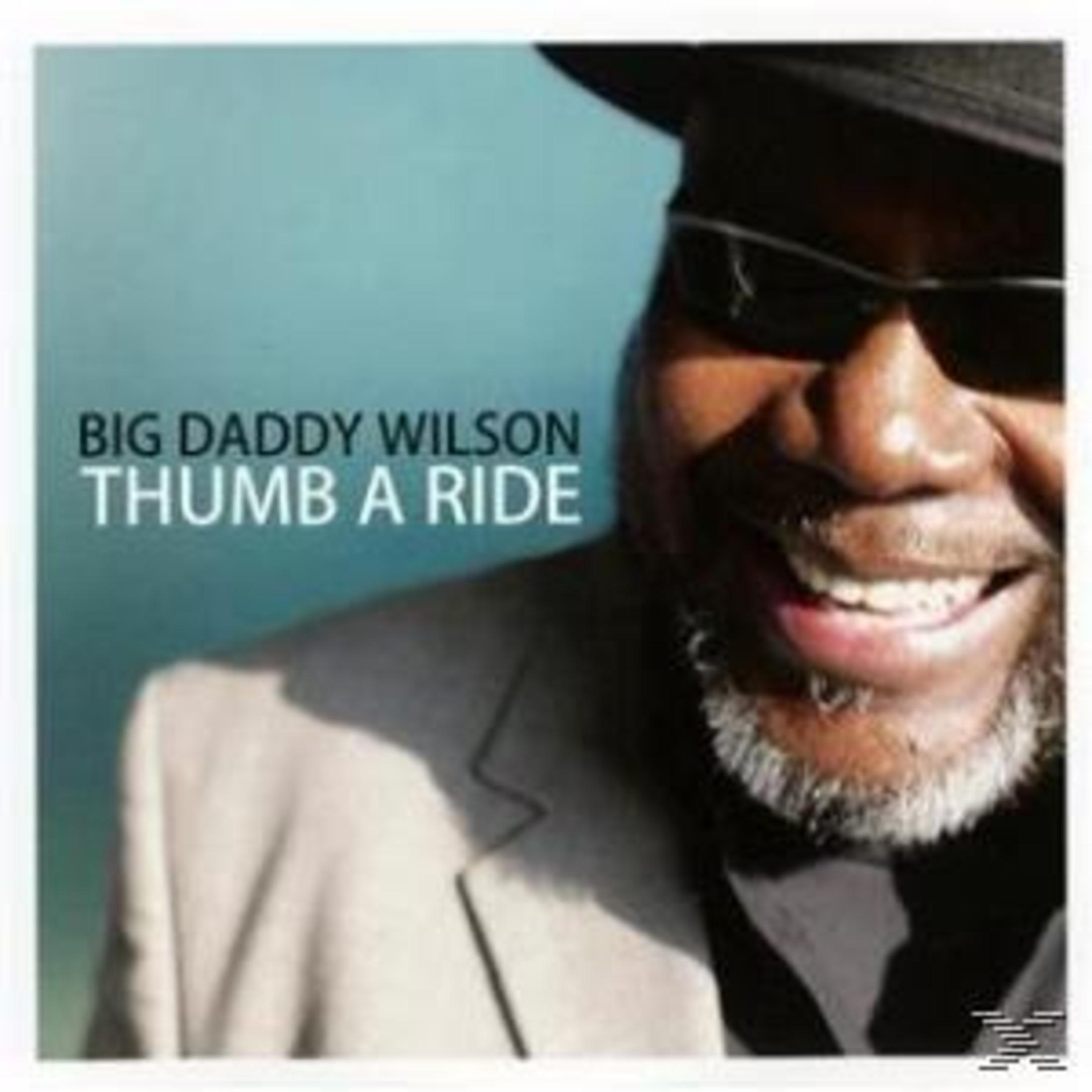 Albumcover mit Big Daddy Wilson in Hut und Sonnenbrille, lächelnd vor blauem Hintergrund.