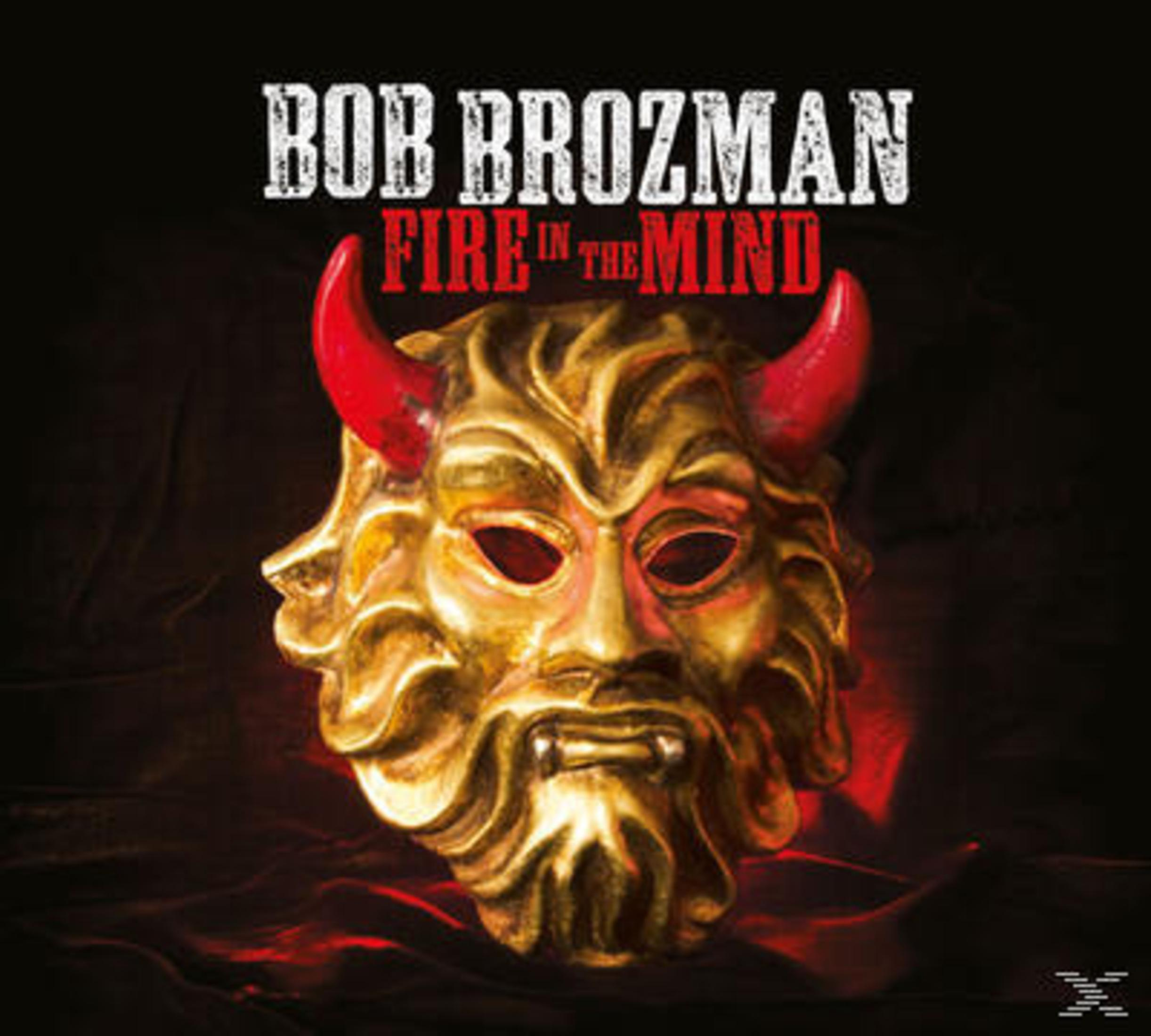Goldene Teufelsmaske mit roten Hörnern und dem Text "Bob Brozman Fire in the Mind" auf schwarzem Hintergrund.