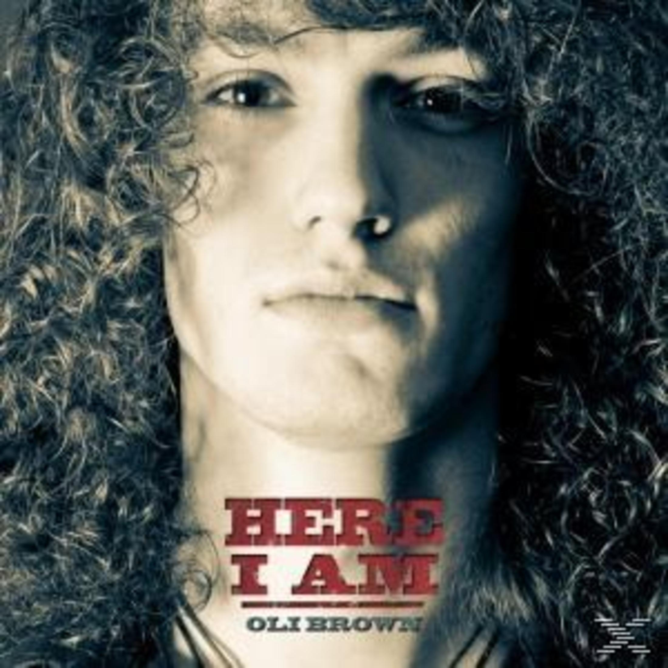 Porträt eines jungen Mannes mit langen lockigen Haaren und dem Text Hier I Am Oli Brown.