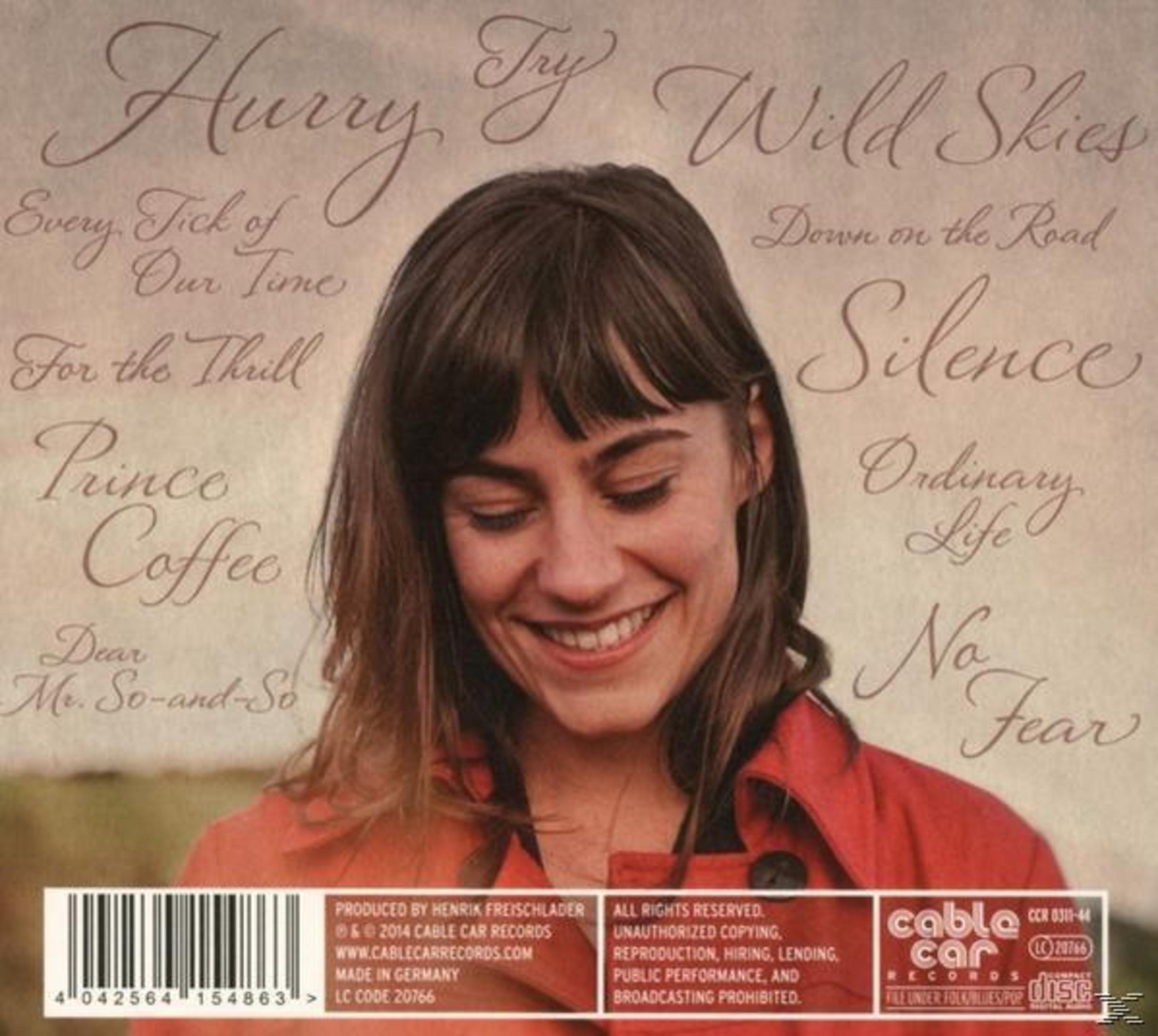 Albumcover mit einer lächelnden Frau in rot und umgeben von Songtiteln und Barcode.