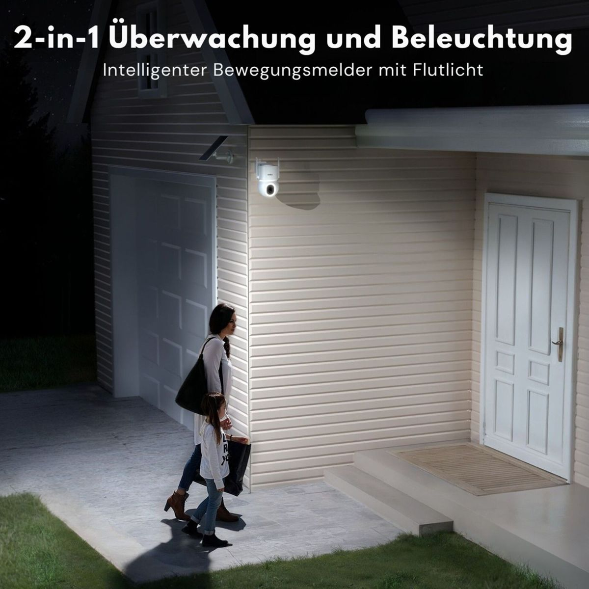Eine Überwachungskamera mit Flutlicht beleuchtet nachts eine Frau und ein Kind vor einem Haus.