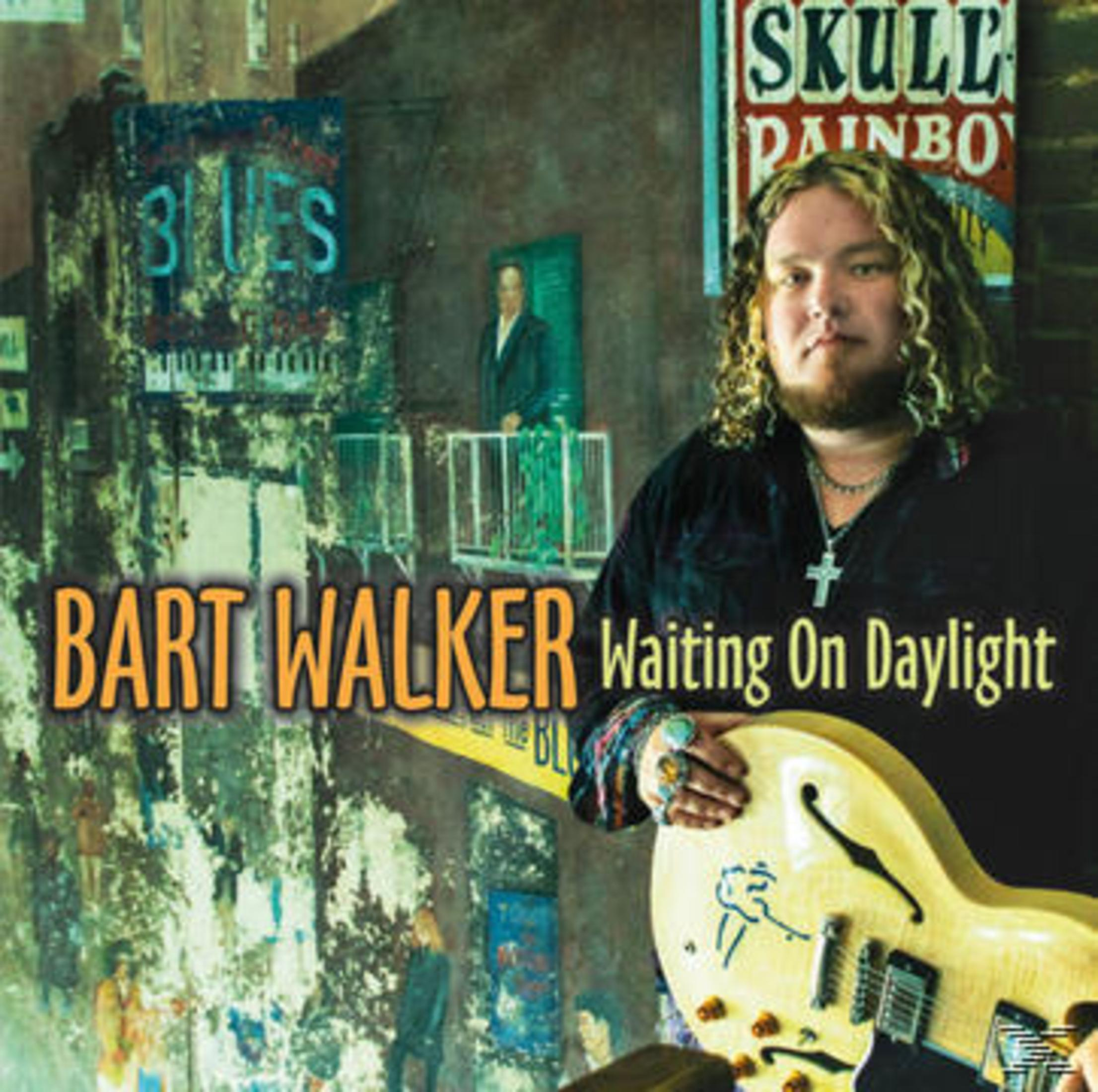 Bart Walker mit Gitarre vor einer Wand mit Blues-Plakaten.