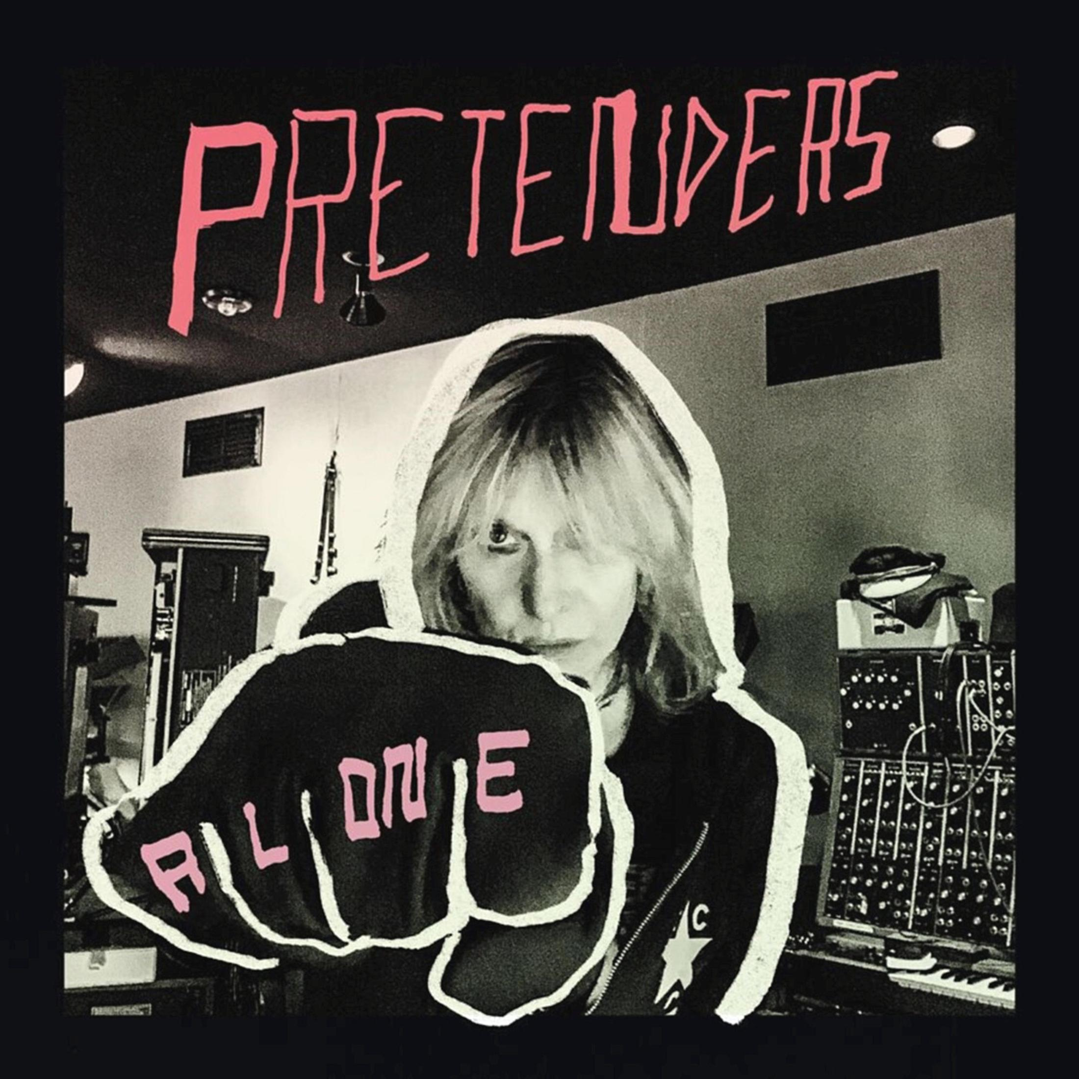 Albumcover der Pretenders mit 'Alone'. Eine Frau in Hoodiejacke ballt eine Faust in die Kamera, mit rotem Text.