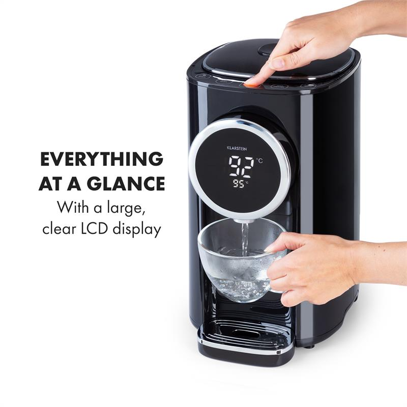 Eine Hand bedient einen schwarzen Heißwasserdispenser, während Wasser in eine Tasse fließt.