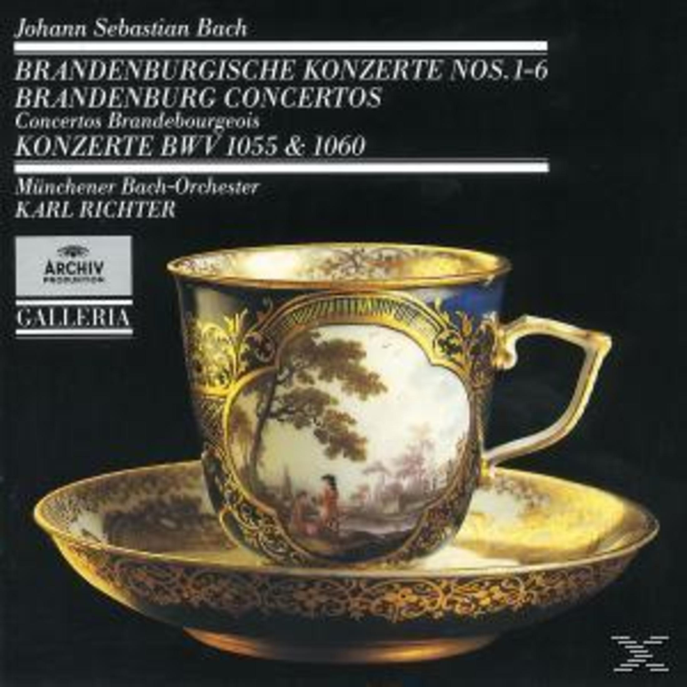 Eine verzierte blau-goldene Porzellantasse mit Untertasse und gemalter Landschaft vor dunklem Hintergrund.