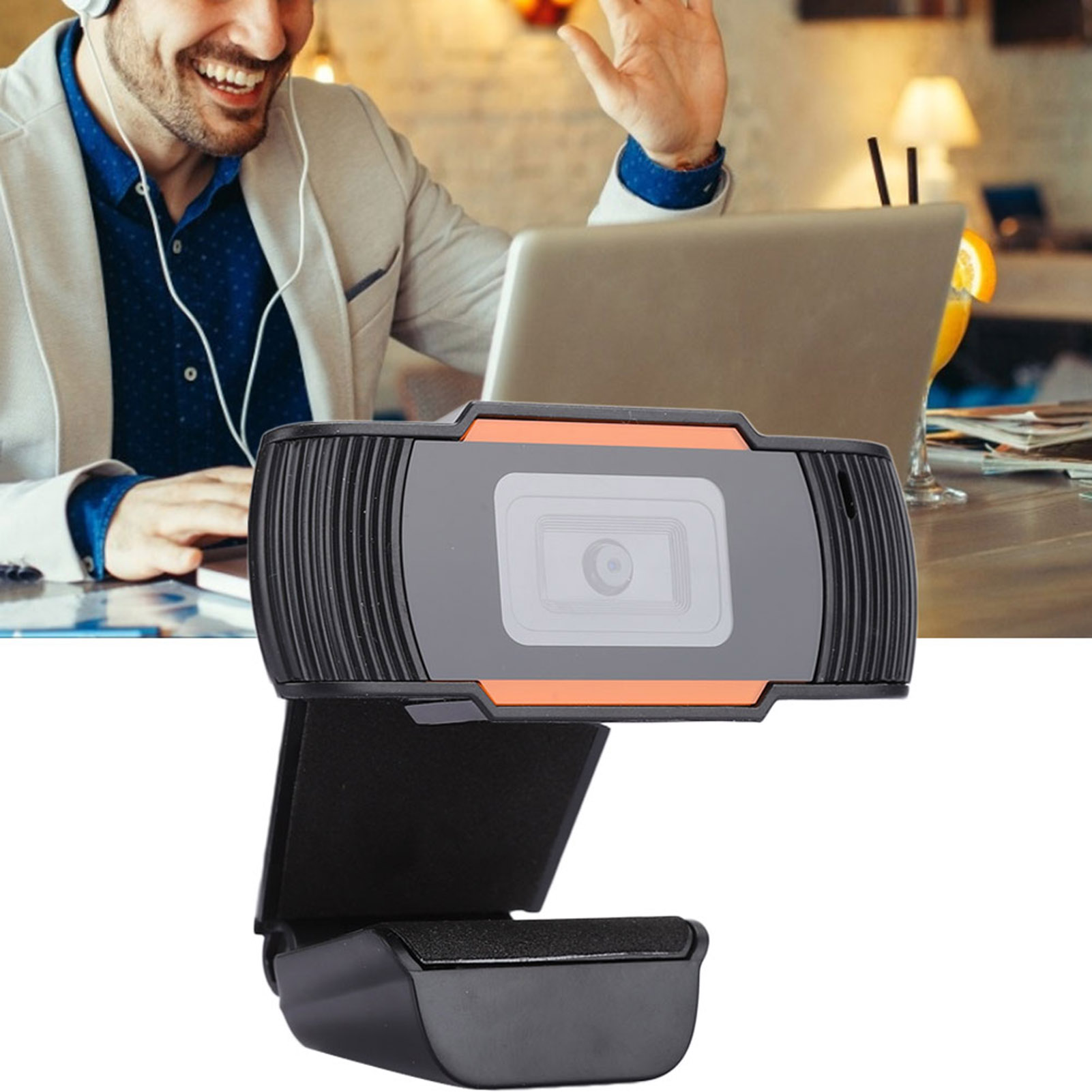 Eine schwarze und graue Webcam mit orangen Akzenten im Vordergrund, dahinter ein Mann bei einem Videoanruf.