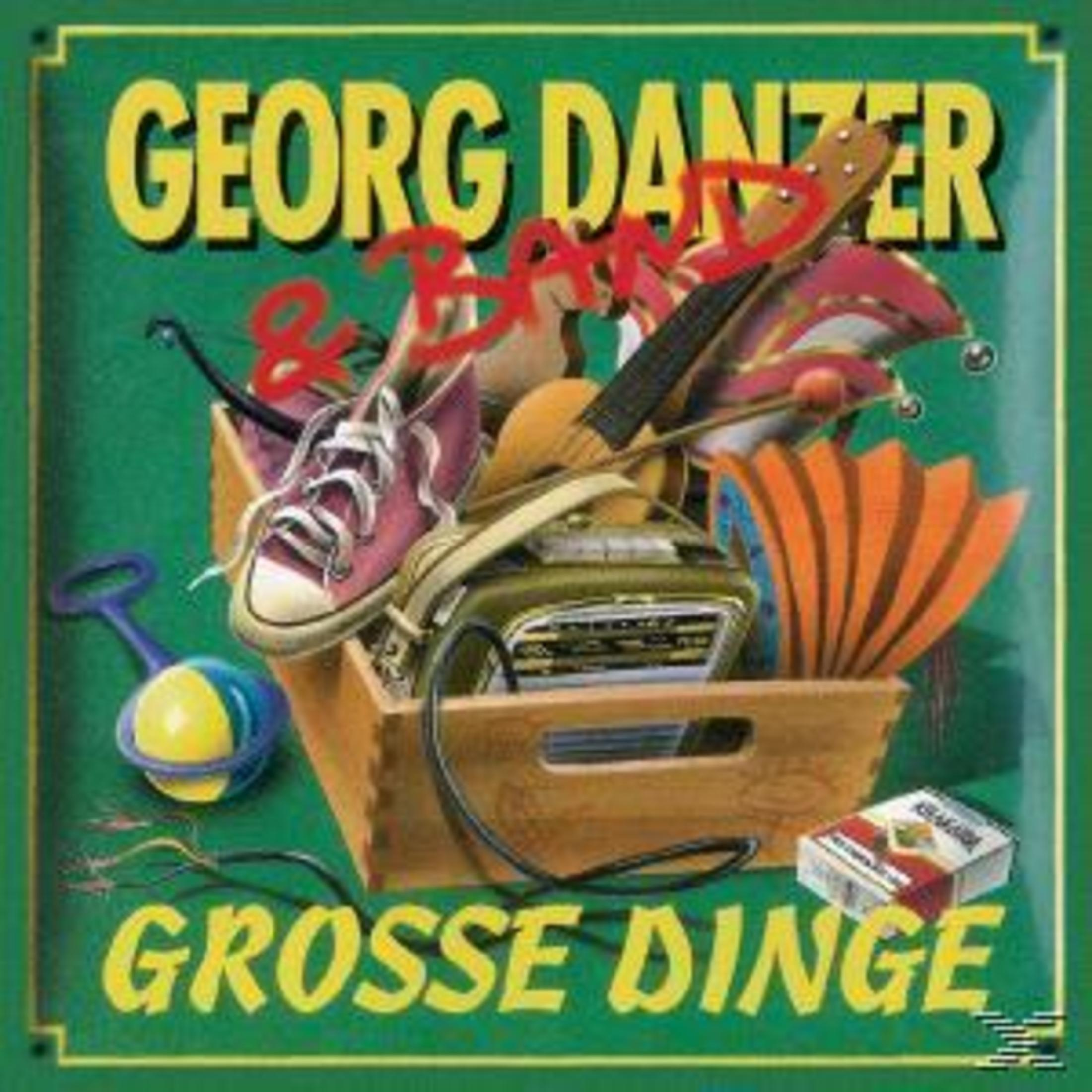 Albumcover mit hölzerner Kiste voller Gegenstände wie Radio, Gitarre und Sneaker, eingerahmt von gelbem Text.