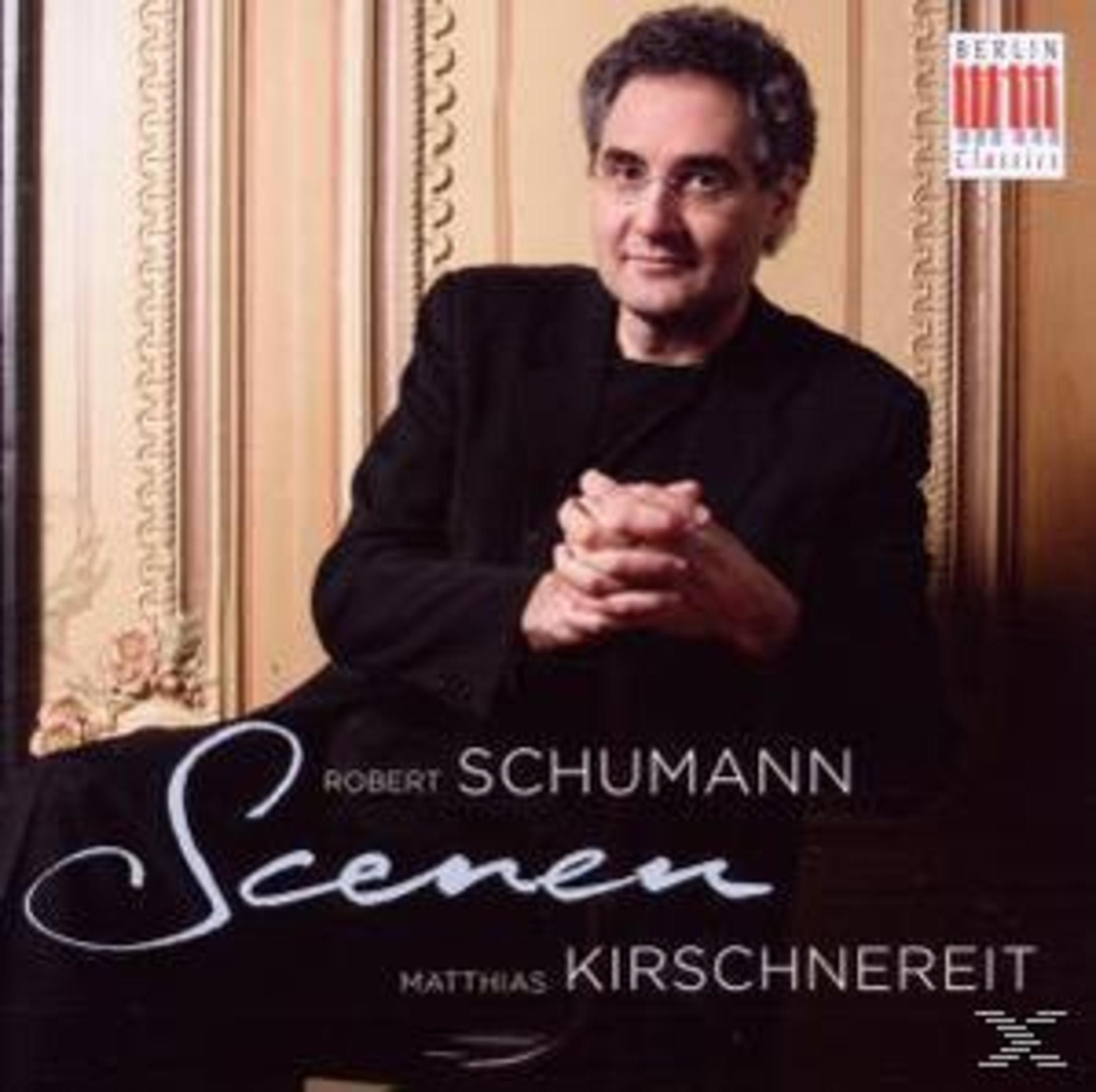 Mann in schwarzem Anzug sitzt vor gemustertem Hintergrund, Hände gefaltet. Text lautet Robert Schumann Scenen.
