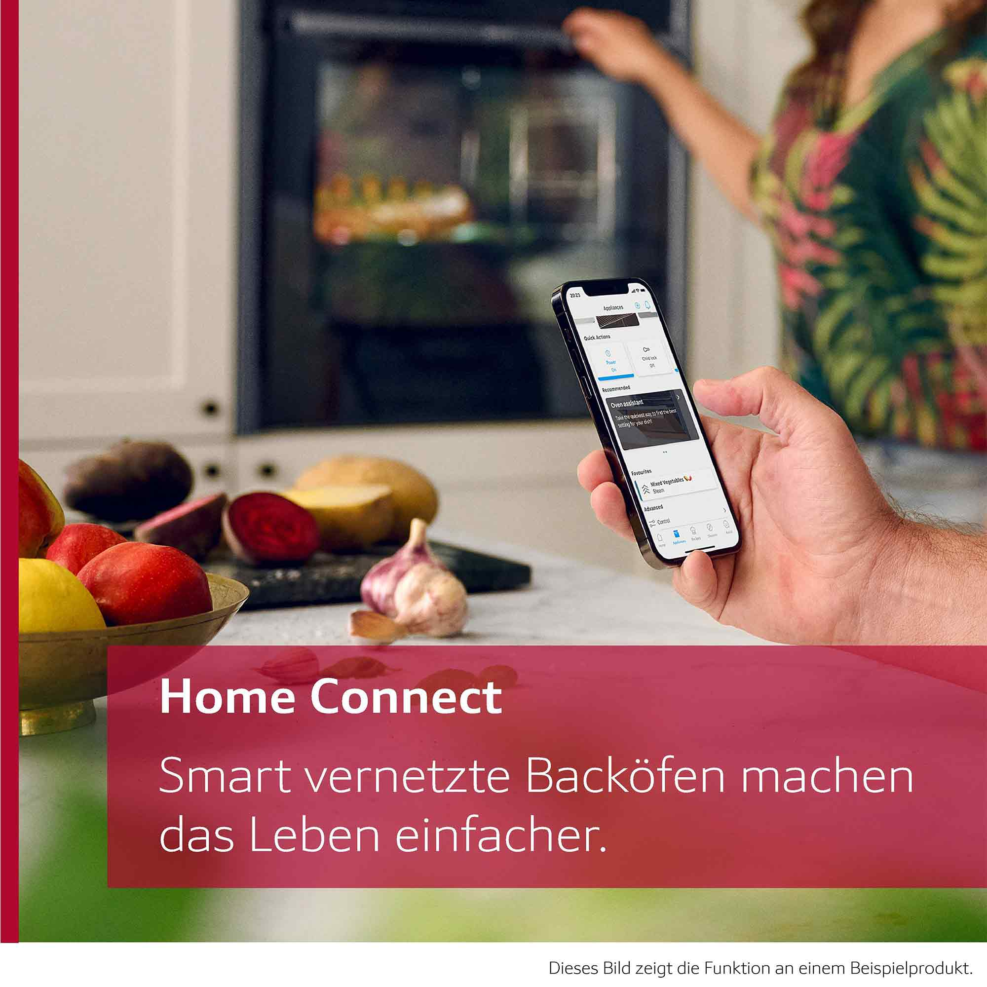 Eine Hand hält ein Smartphone mit geöffneter Backofen-App in einer Küche mit Gemüse im Vordergrund.