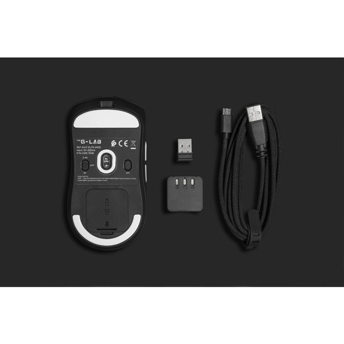 Un ratón de ordenador negro, un receptor USB y un cable de carga negro enrollado sobre fondo oscuro.