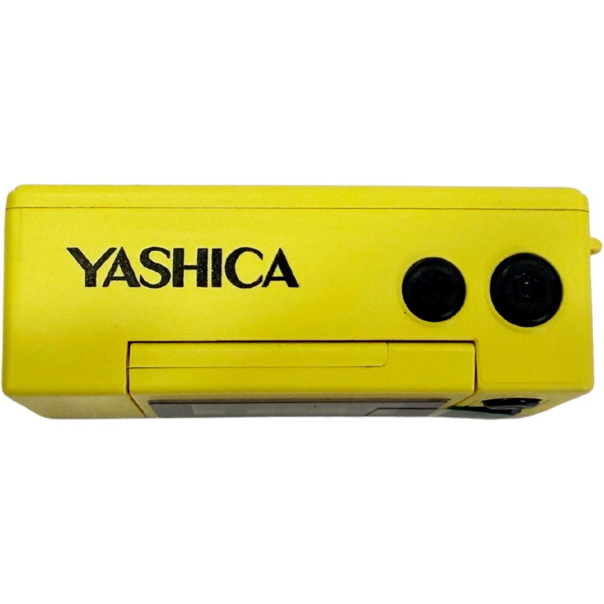 Eine leuchtgelbe Yashica-Kamera mit schwarzen Knöpfen und dem Markennamen in fetten schwarzen Buchstaben auf der Vorderseite.