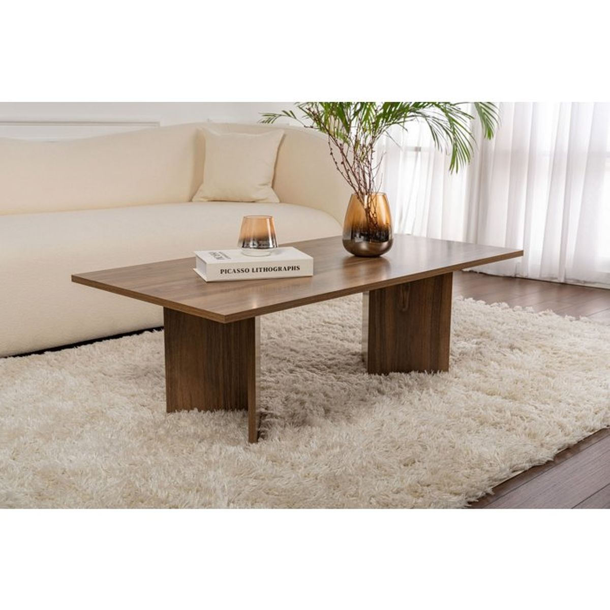 Ein hölzerner Couchtisch steht auf einem flauschigen Teppich vor einem beigen Sofa mit einer Vase und einem Buch.