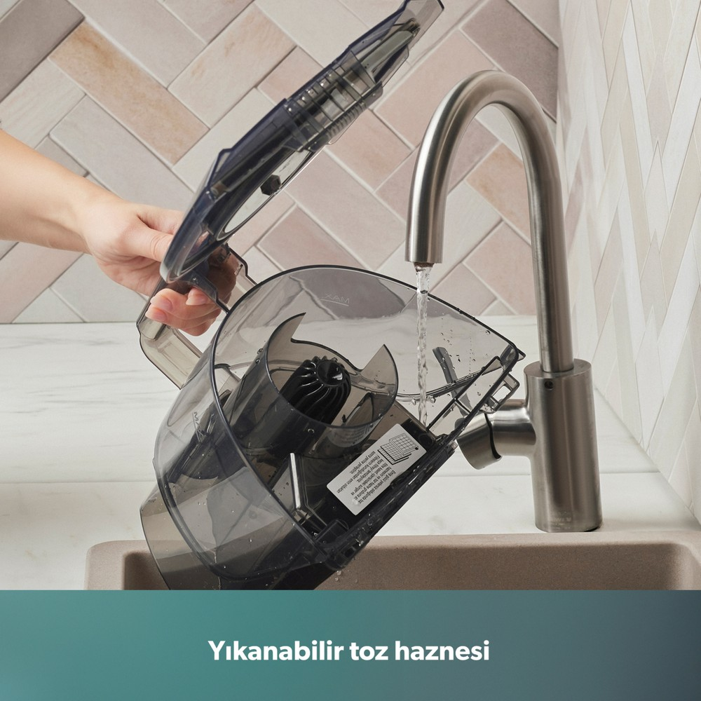 Bir el, süpürgenin haznesini musluk altında yıkıyor.