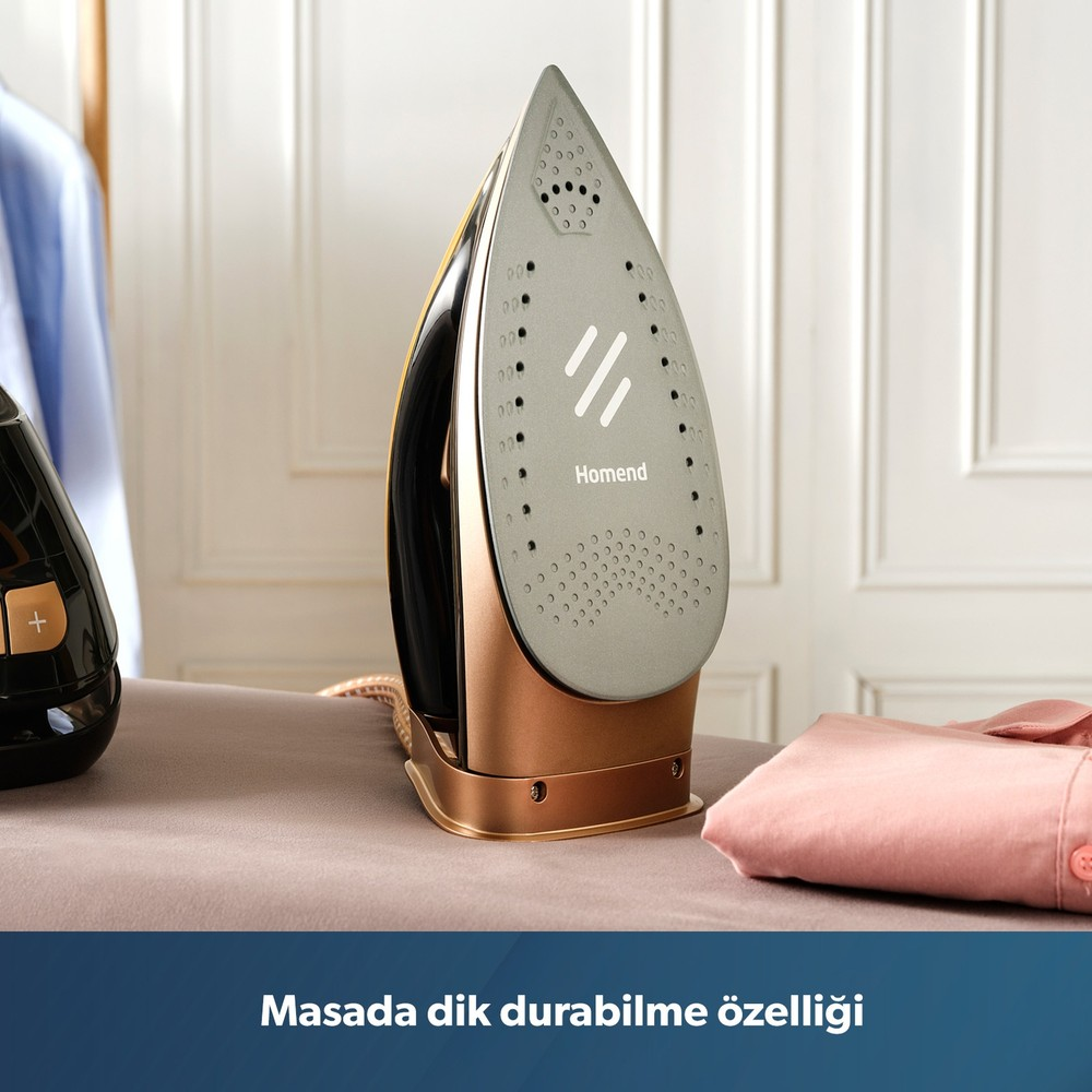 Katlanmış kıyafetlerin yanında masada dik duran altın renkli Homend ütü.