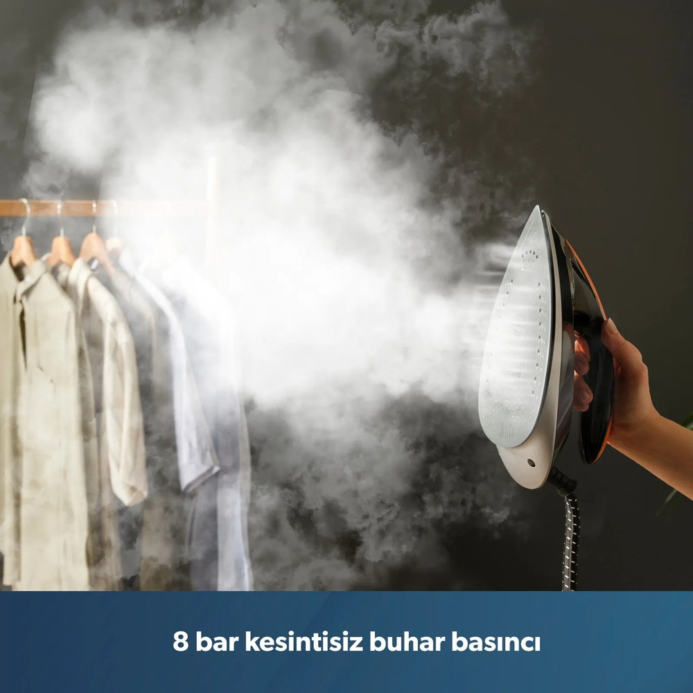 Askıdaki kıyafetlere yoğun buhar veren buharlı ütüyü tutan bir el.