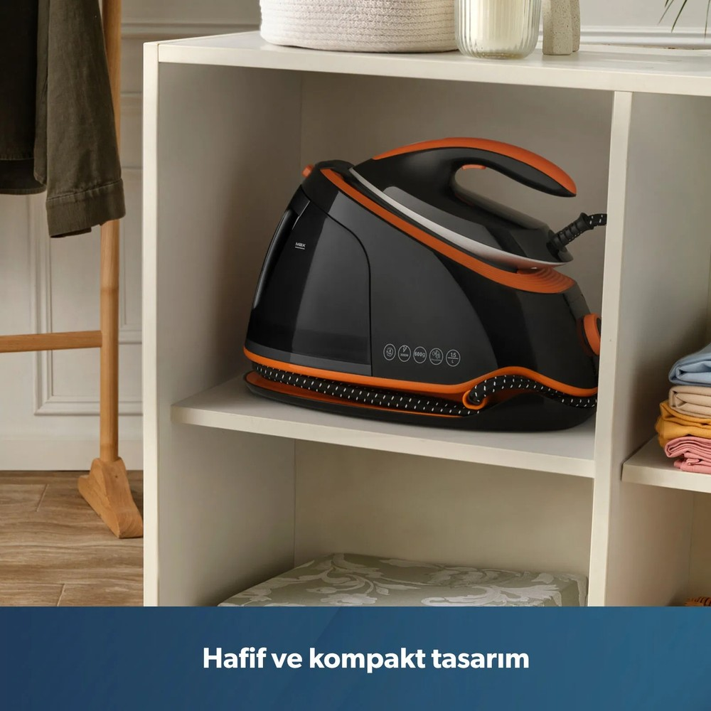 Beyaz bir raf gözünde siyah ve turuncu renkte bir buharlı ütü duruyor.