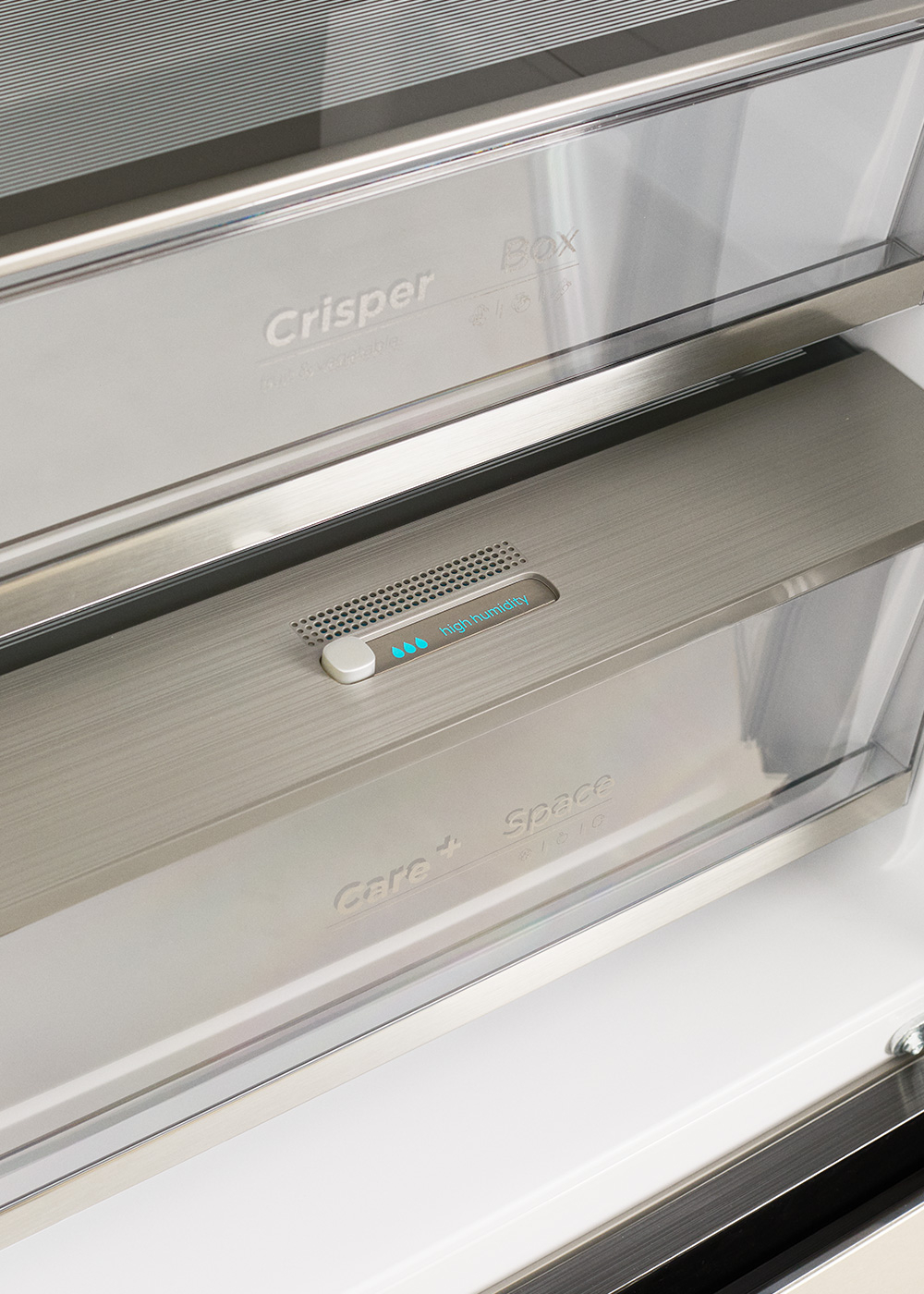 Primer plano de los cajones verduleros del refrigerador con un control de humedad en el borde frontal.