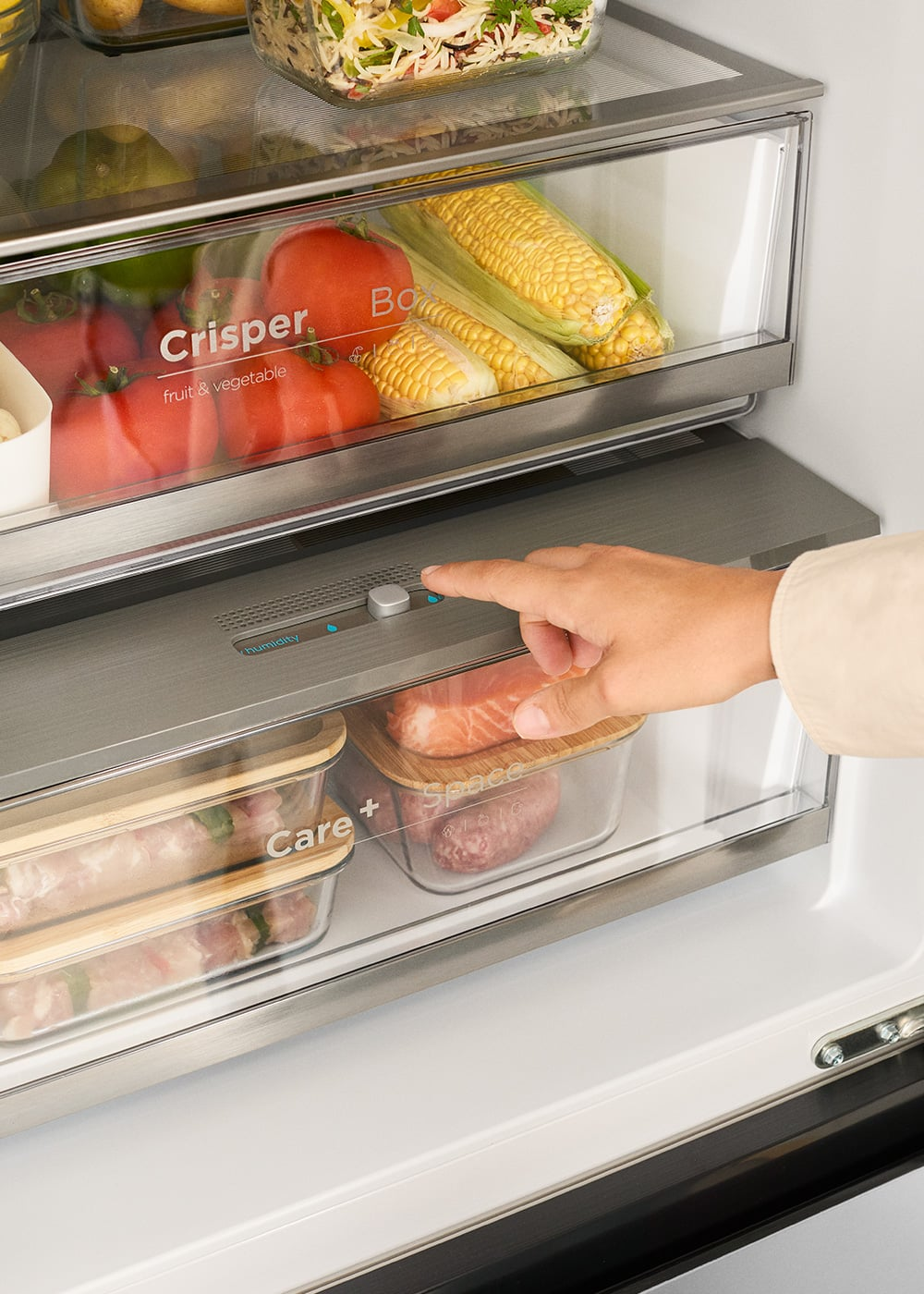 Mano ajustando control de humedad en refrigerador moderno con verduras y carne.