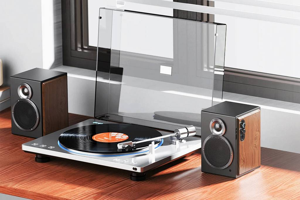 Nowoczesny gramofon z odtwarzaną płytą winylową stoi na drewnianym biurku między dwoma głośnikami.