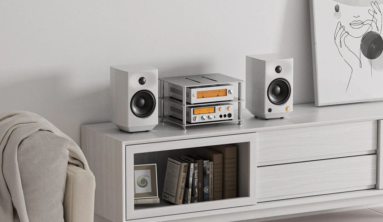 Dwa biale glosniki i wzmacniacz hi-fi na jasnej drewnianej szafce z ksiazkami.