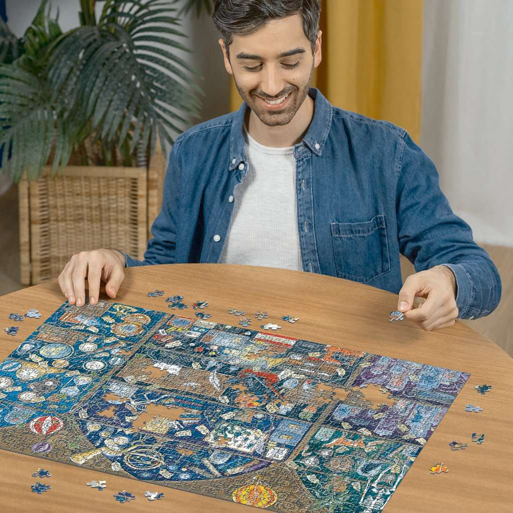 Ein Mann sitzt an einem Holztisch und setzt ein großes Puzzle zusammen.