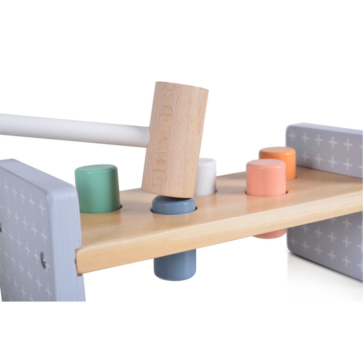 Ein Holzspielzeughammer schlägt auf einen blauen Pflock einer bunten Klopfbank.