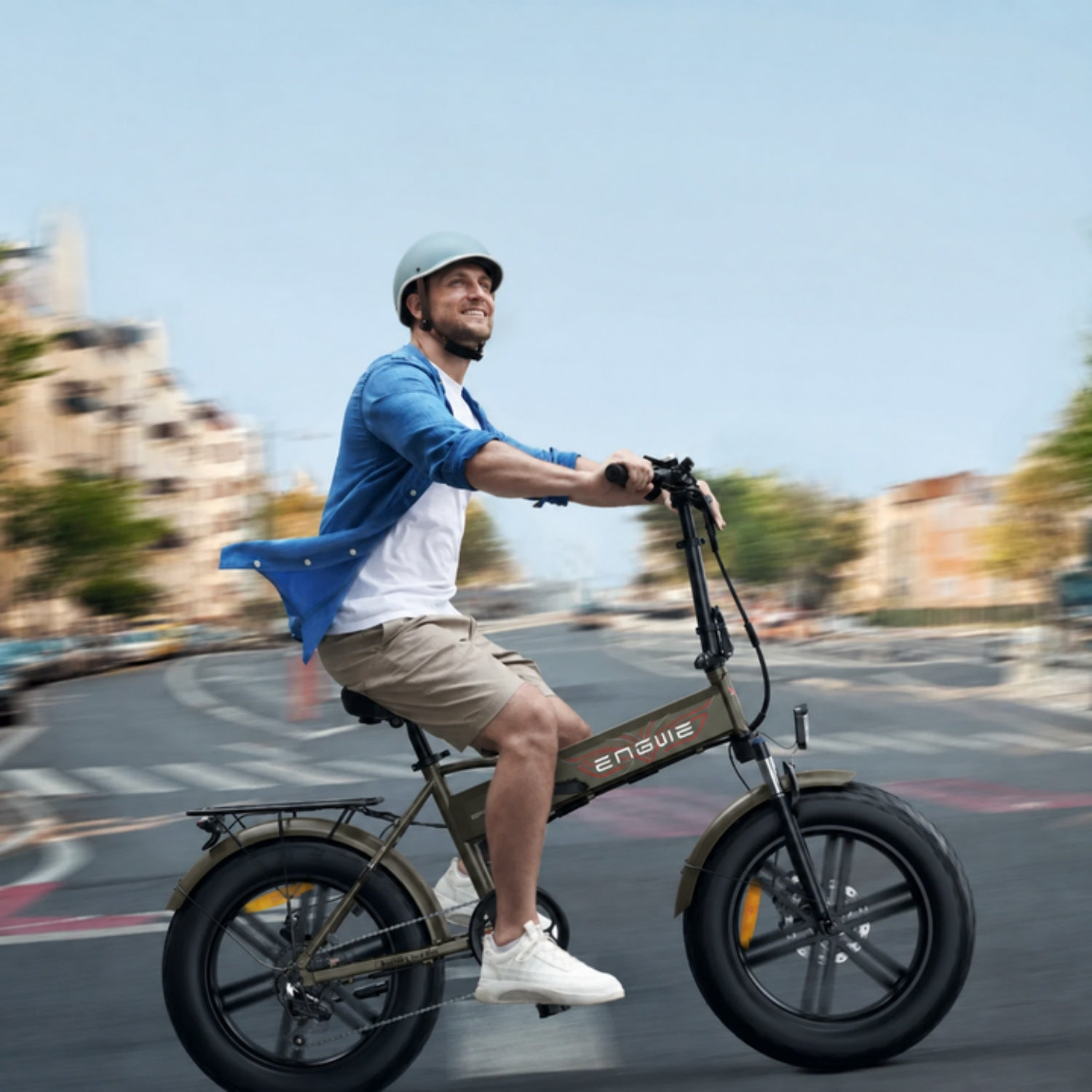 Un uomo con casco guida una e-bike verde oliva su una strada, con sfondo sfocato.