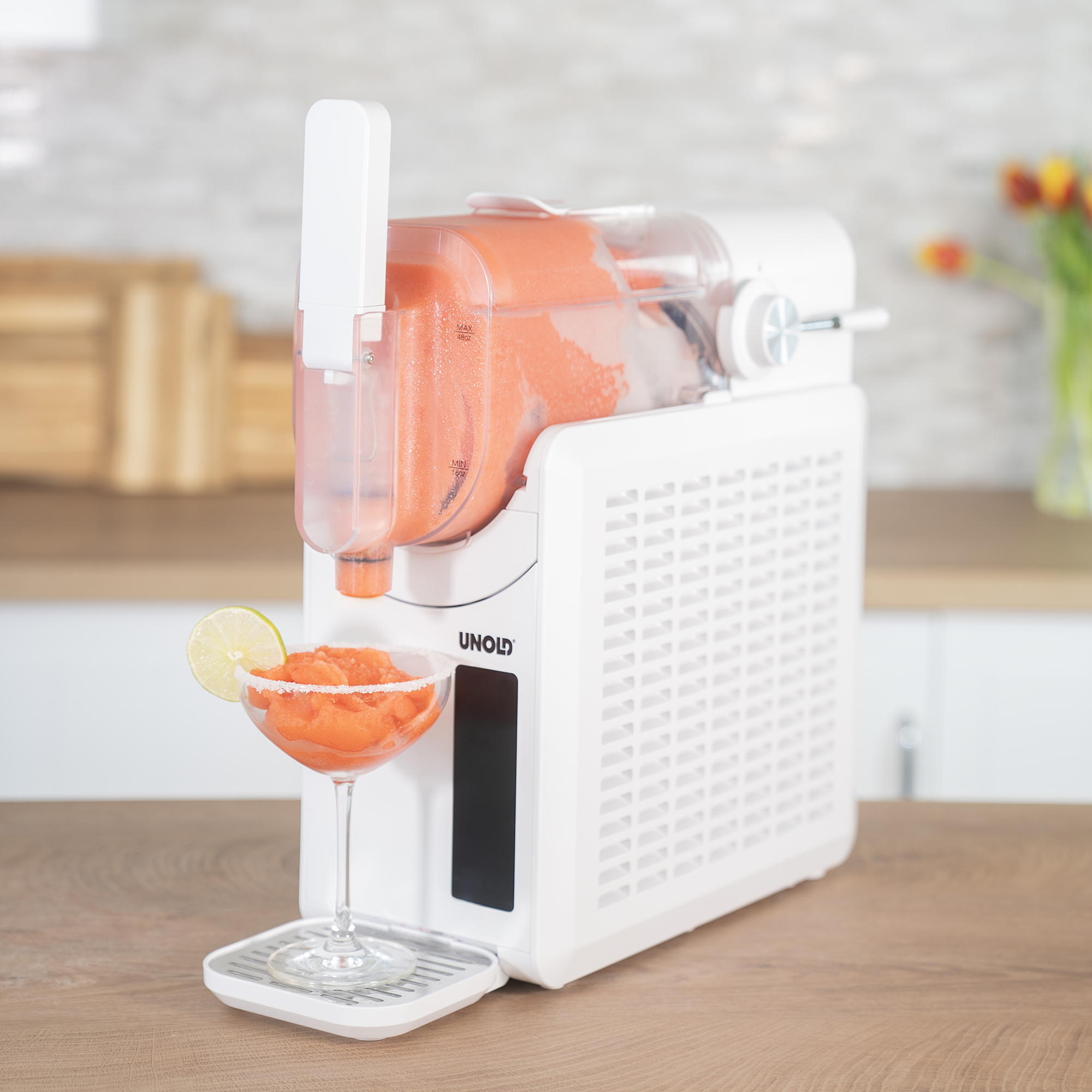 Eine weiße Unold Slush-Maschine auf einer Holzarbeitsplatte füllt einen Cocktail mit Limette.