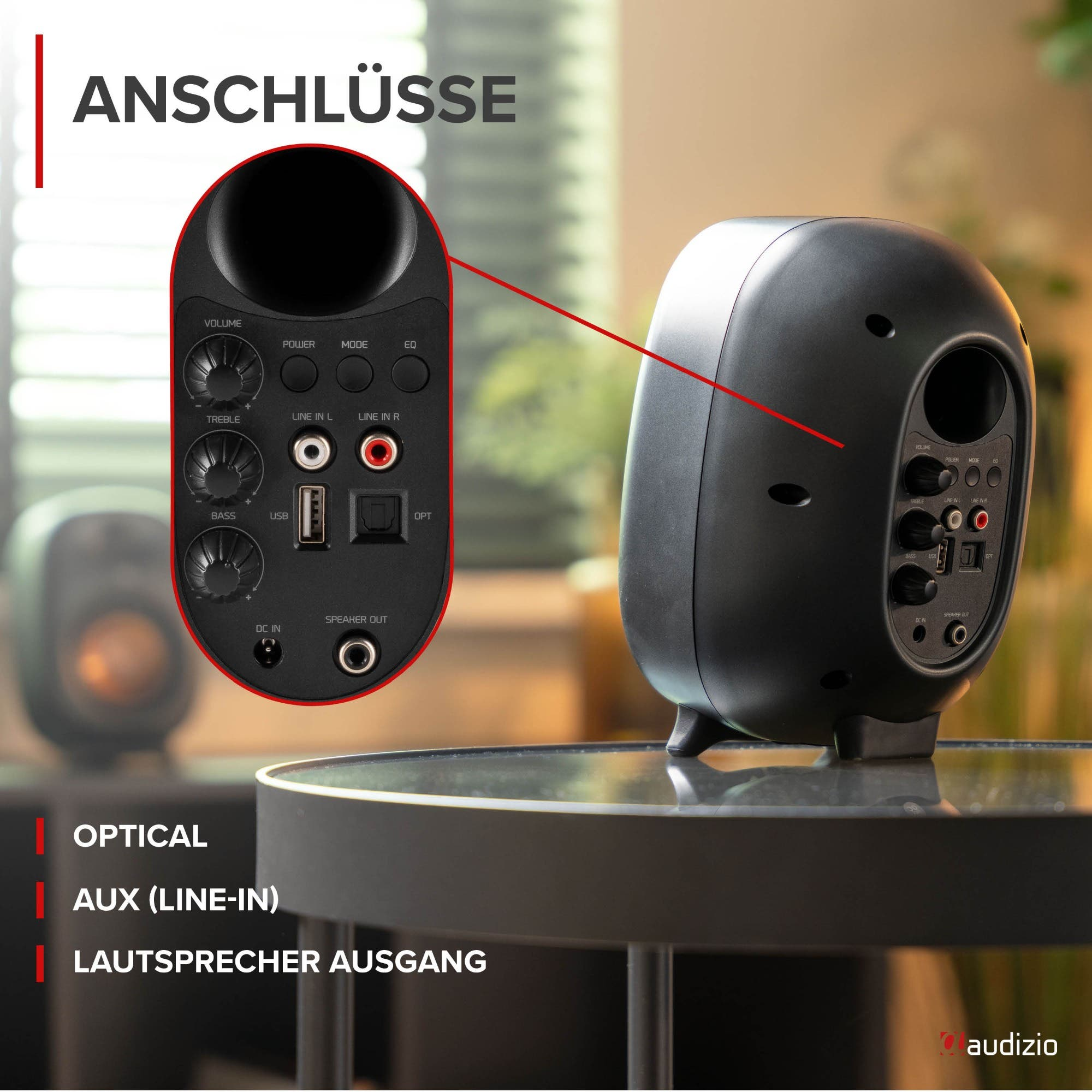 Rückseite eines schwarzen Audizio-Lautsprechers mit verschiedenen Anschlüssen auf einem Glastisch.