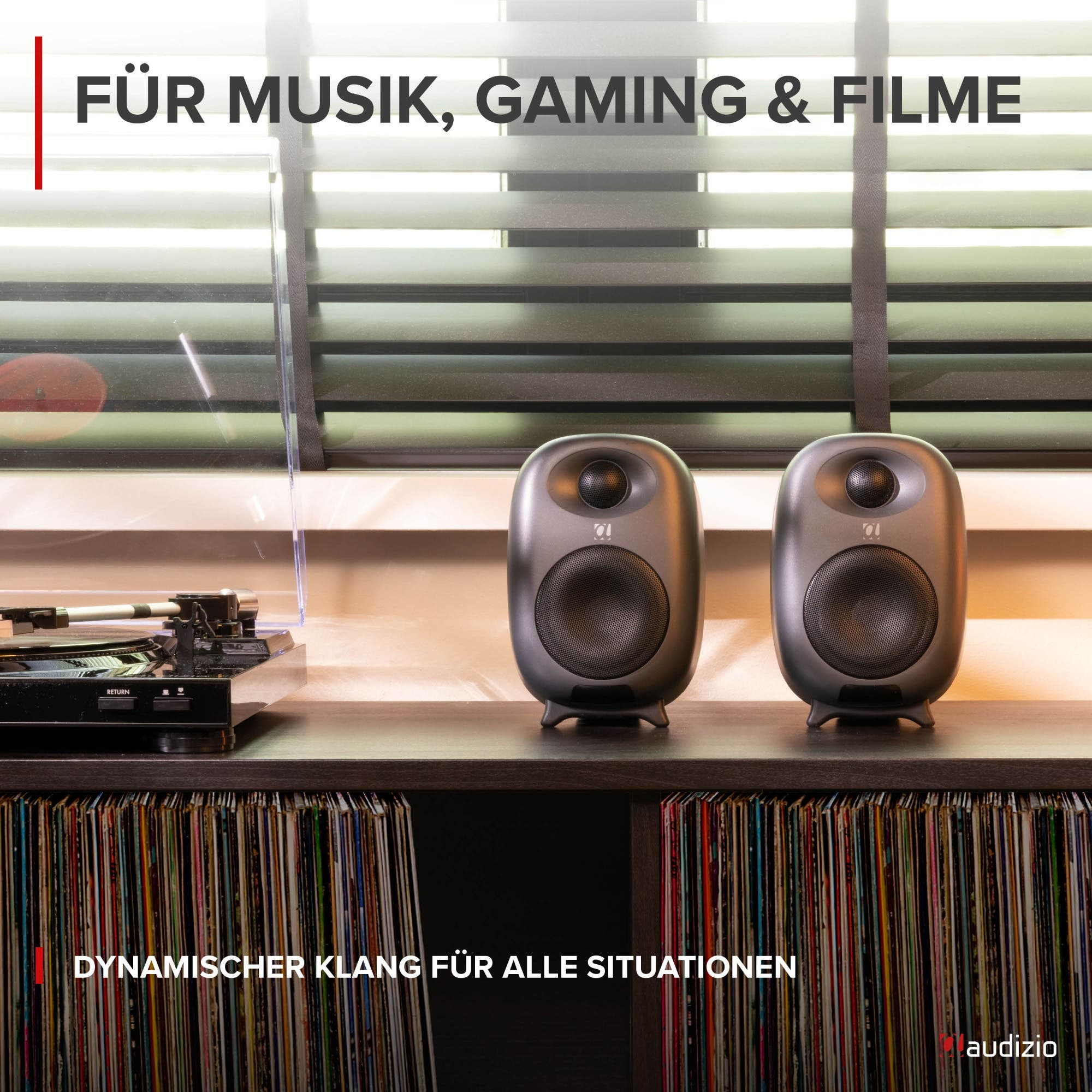 Zwei schwarze Audiolautsprecher und ein Plattenspieler auf einem Regal vor Schallplatten.