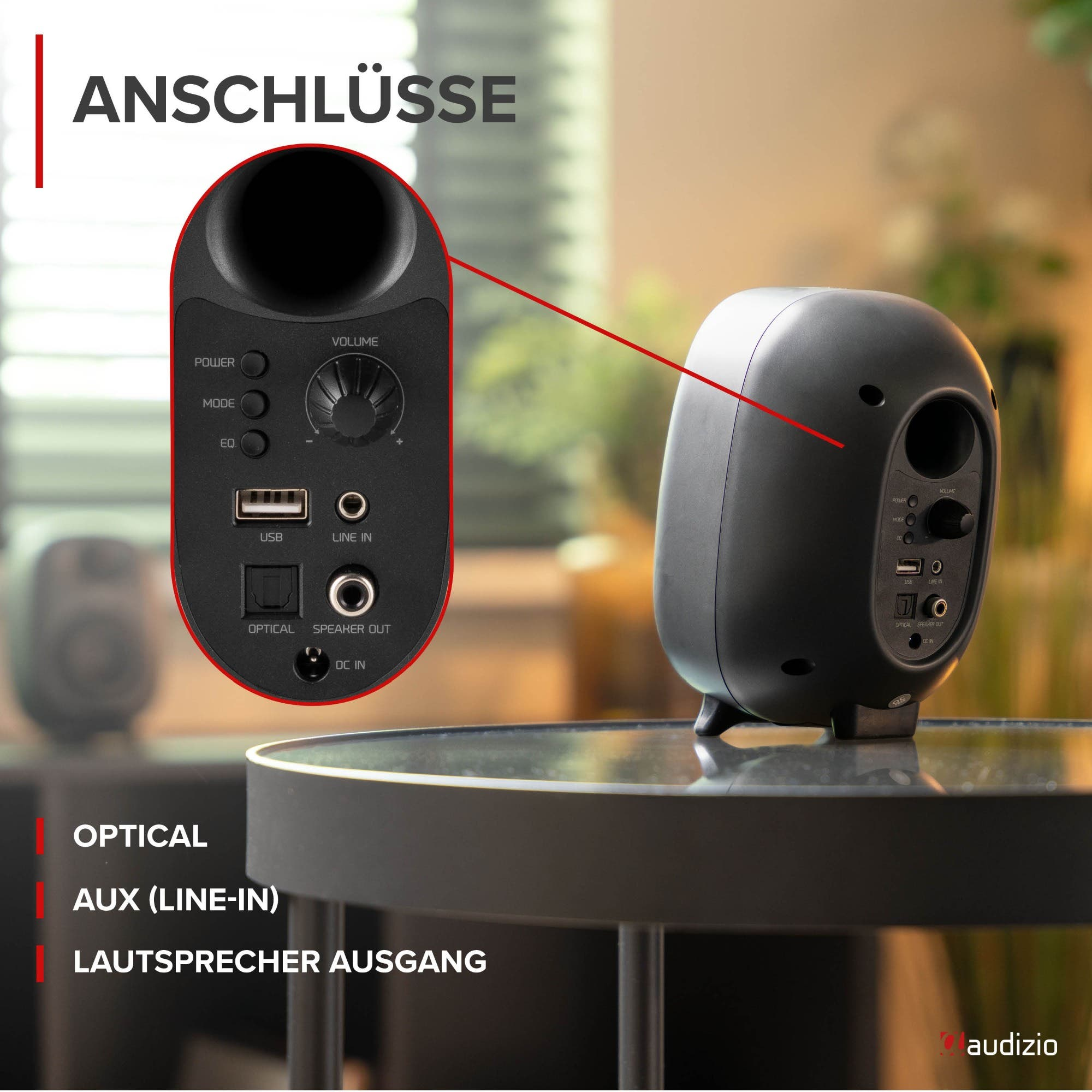 Rückseite eines schwarzen Audizio-Lautsprechers mit Nahansicht der Anschlüsse und Regler auf einem Glastisch.