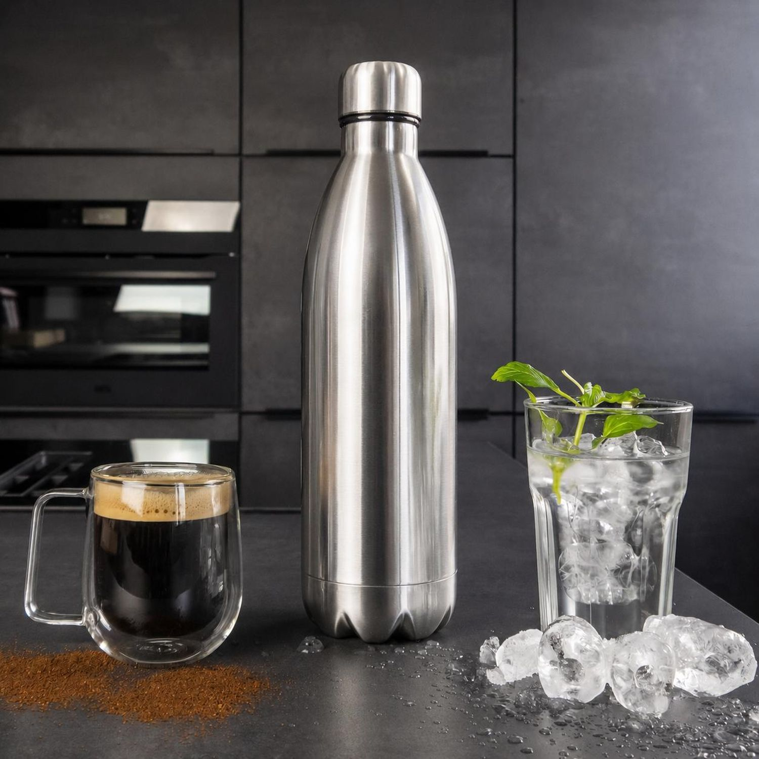 Edelstahl-Thermosflasche auf der Arbeitsplatte zwischen Kaffeetasse und Eiswasserglas.