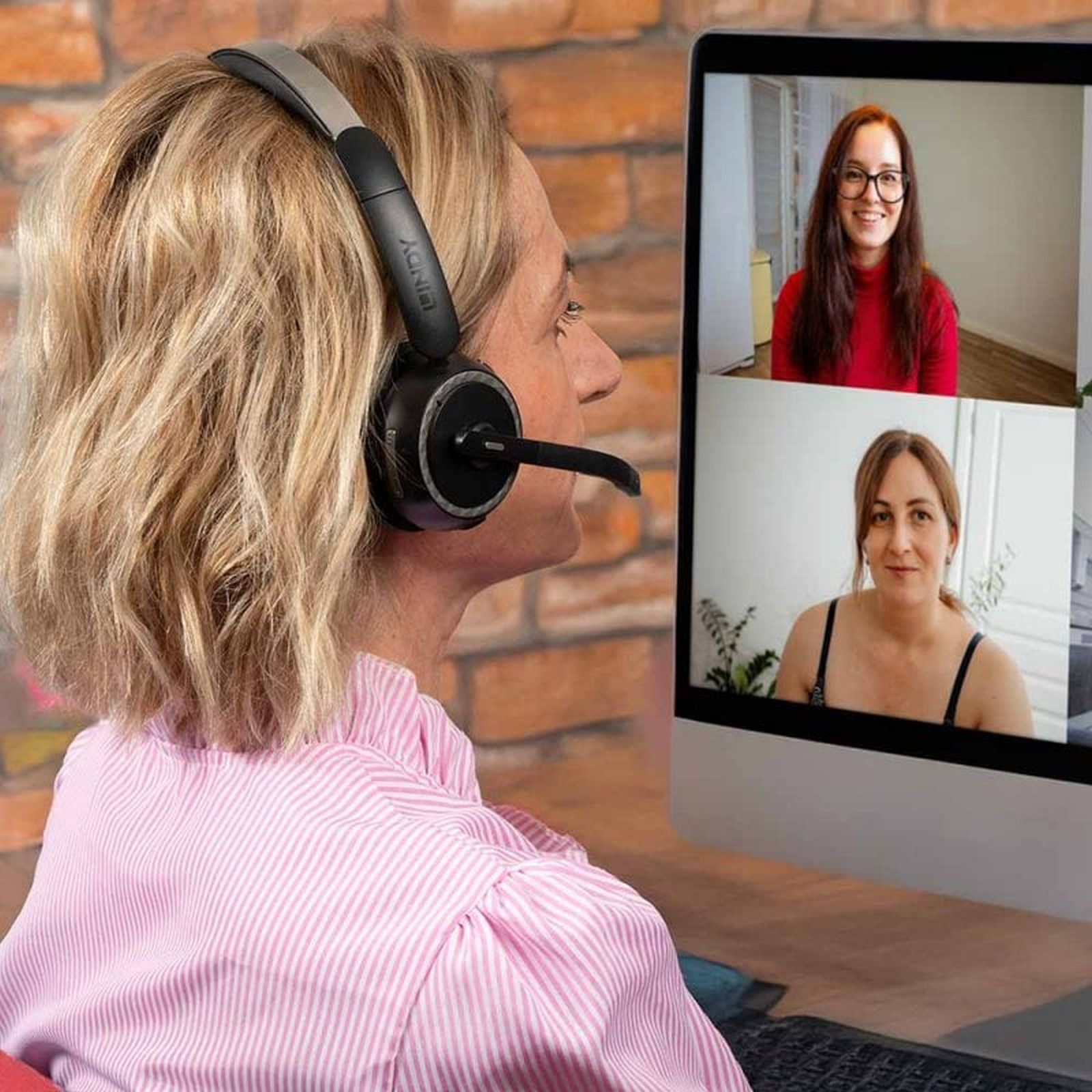 Mujer rubia con auriculares en una videollamada en su ordenador con otras dos mujeres.