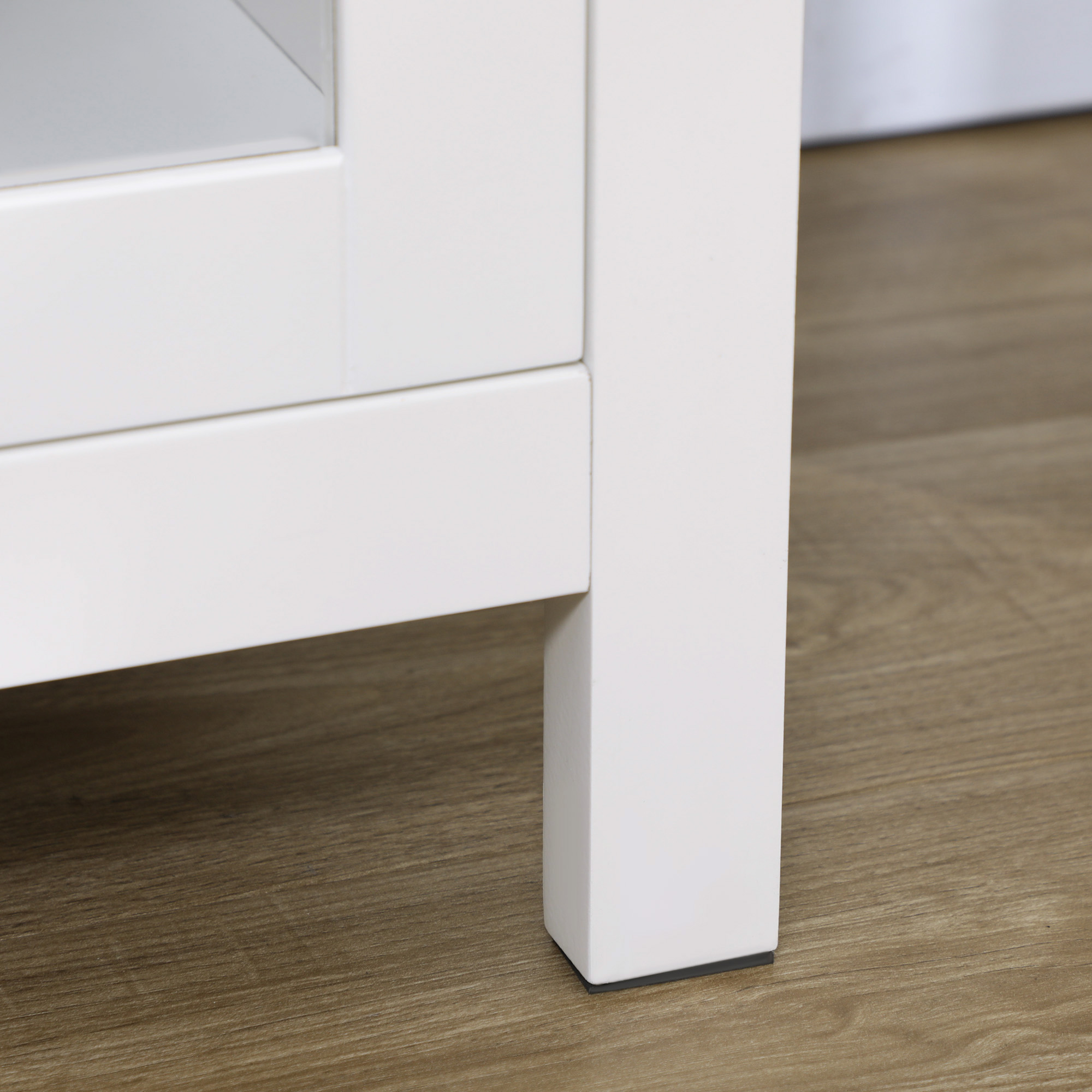 Primer plano de la pata de un mueble de madera blanca sobre suelo de madera.