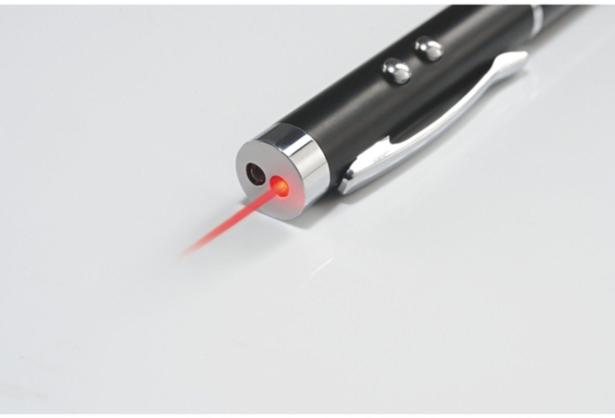 Un puntatore laser nero con clip argentata emette un raggio rosso su una superficie chiara.