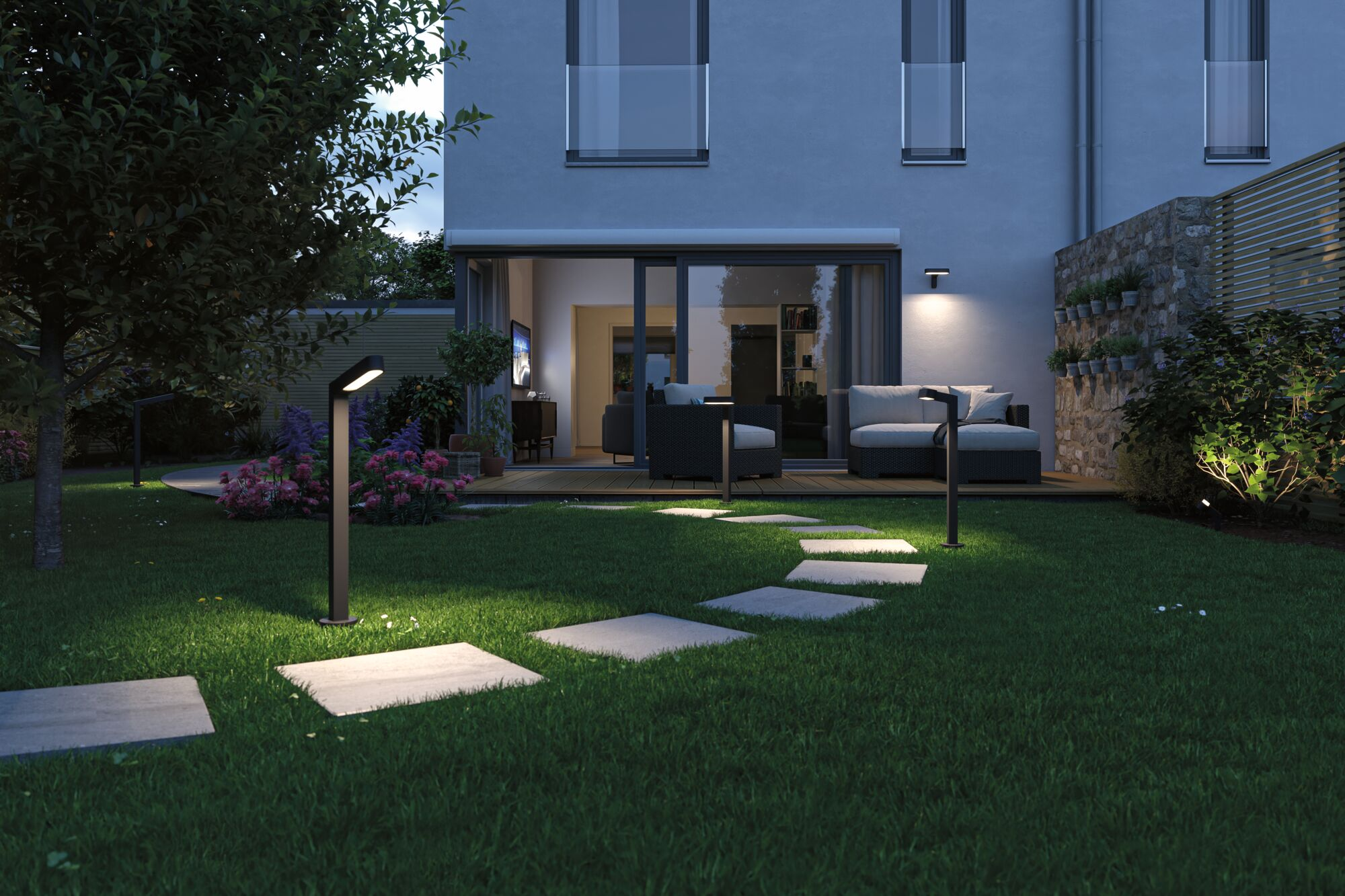Beleuchteter Gartenweg mit modernen Wegeleuchten und Steinen im Dunkeln vor einem Haus.