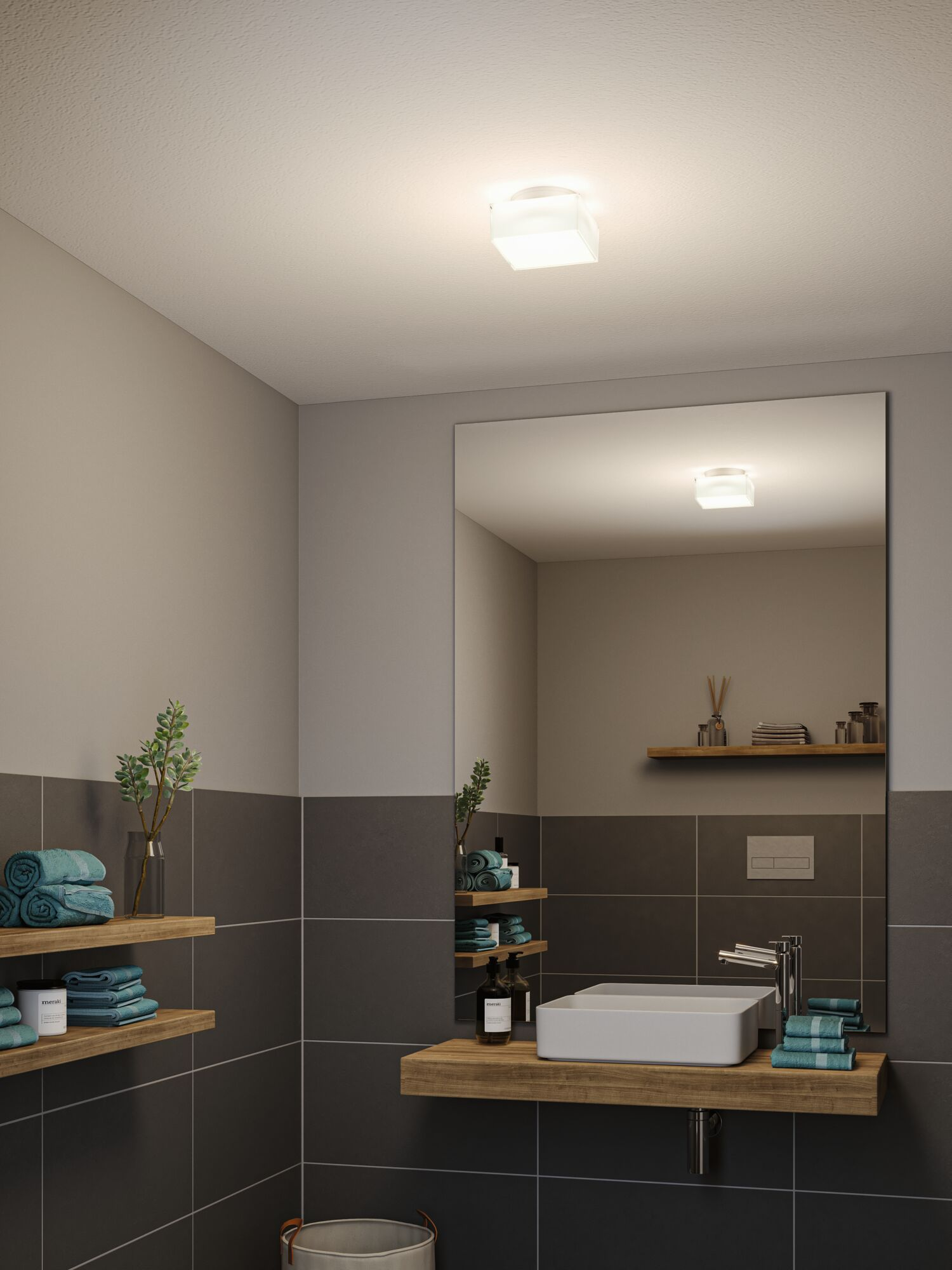 Modernes Badezimmer mit Waschbecken auf Holzplatte, großem Spiegel, grauen Fliesen und Deckenleuchte.